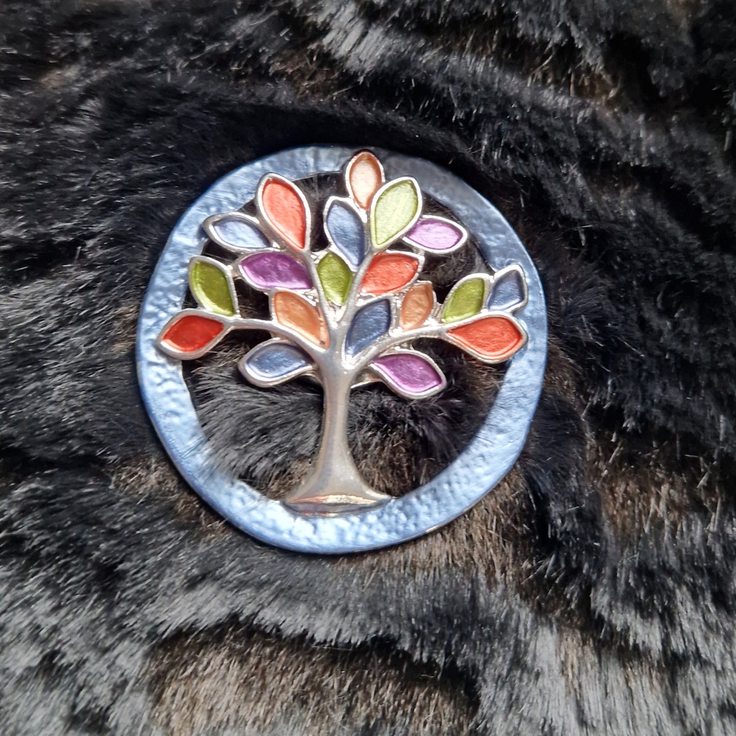 Colorful tree-shaped brooch on a fur surface
