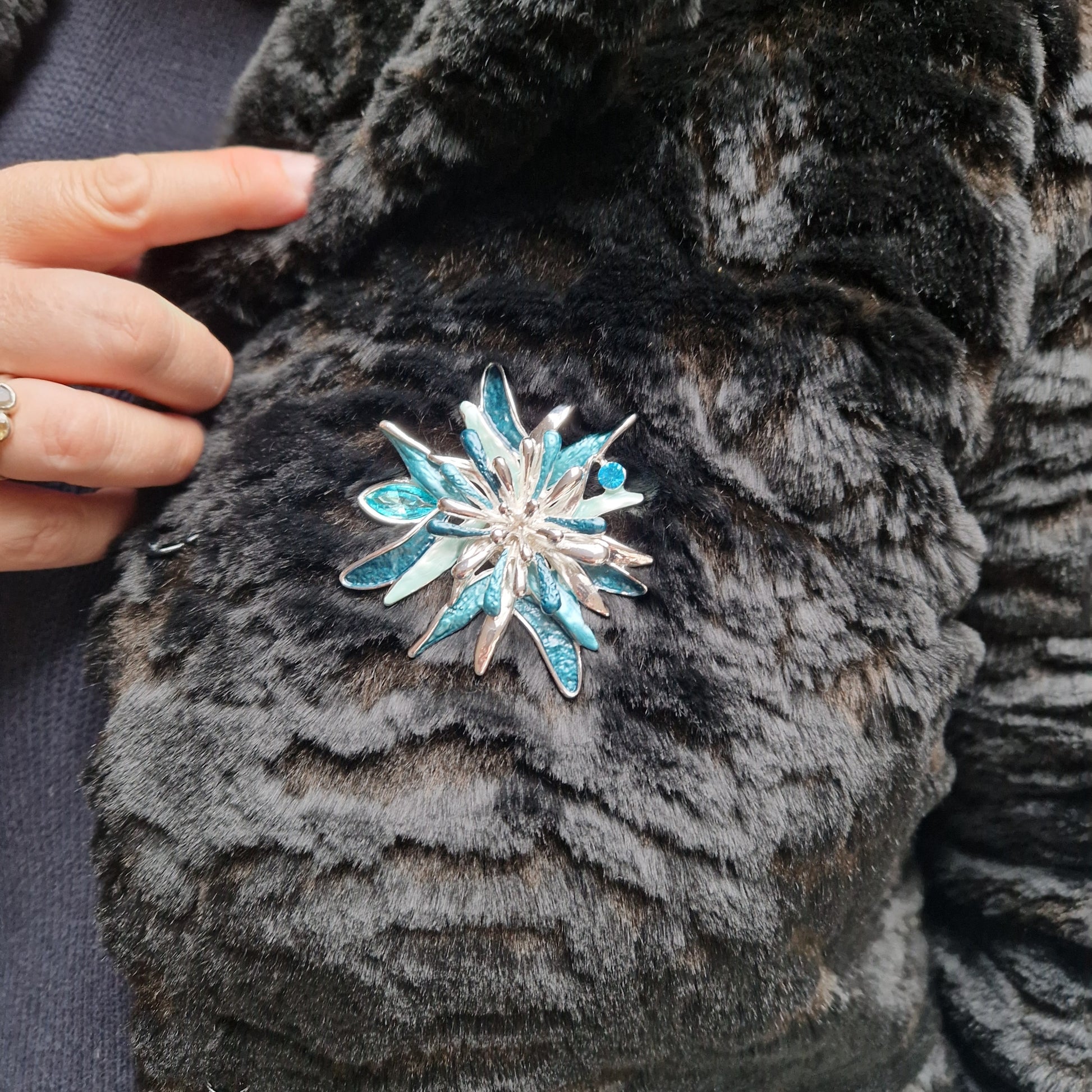 Silver and blue snowflake brooch on a dark fur coat