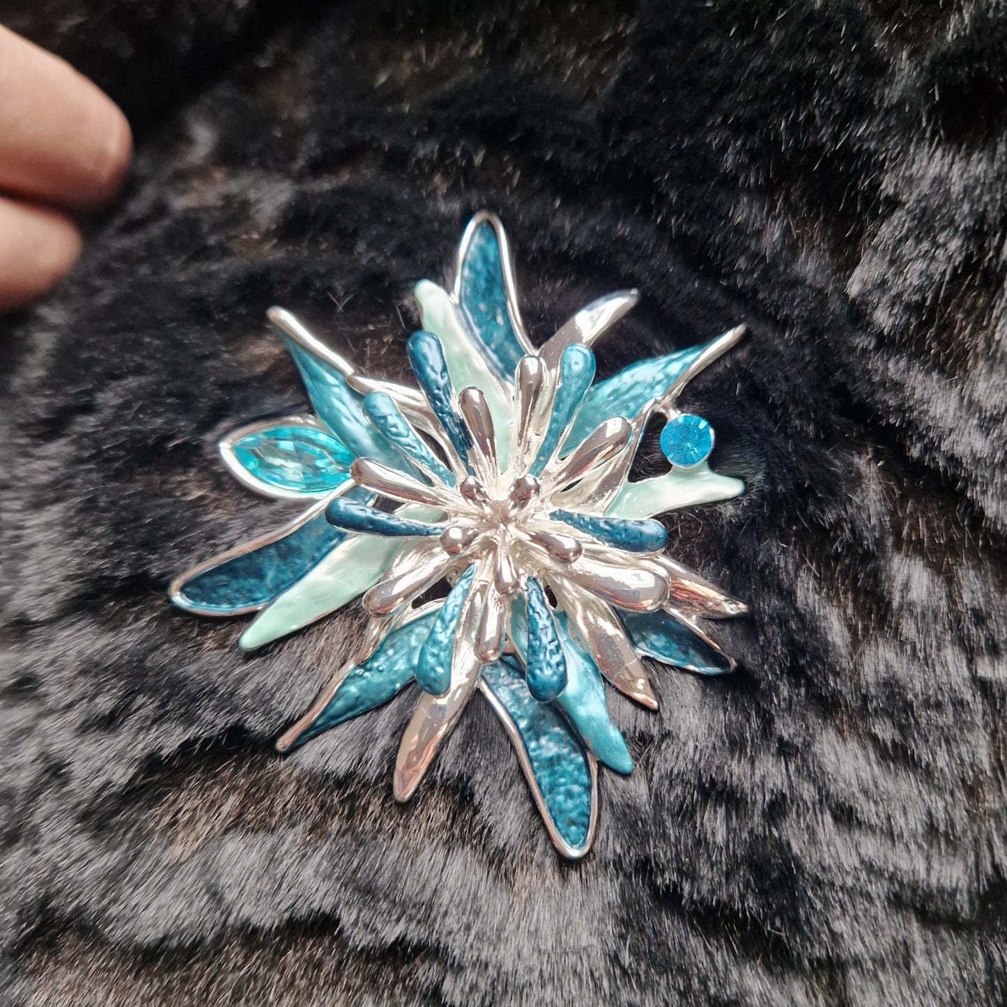 Blue and silver star-shaped brooch on a fur surface