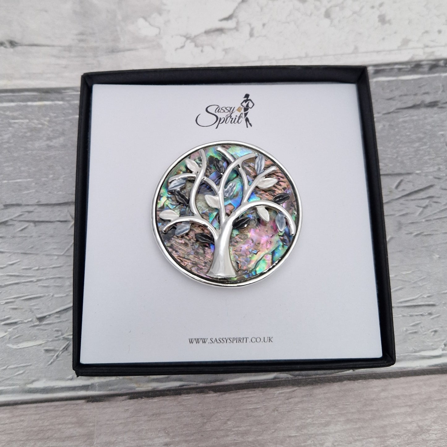 Paua Shell inlaid brooch decorated with a silver tone tree of life. Presented in a Sassy Spirit Gift Box.