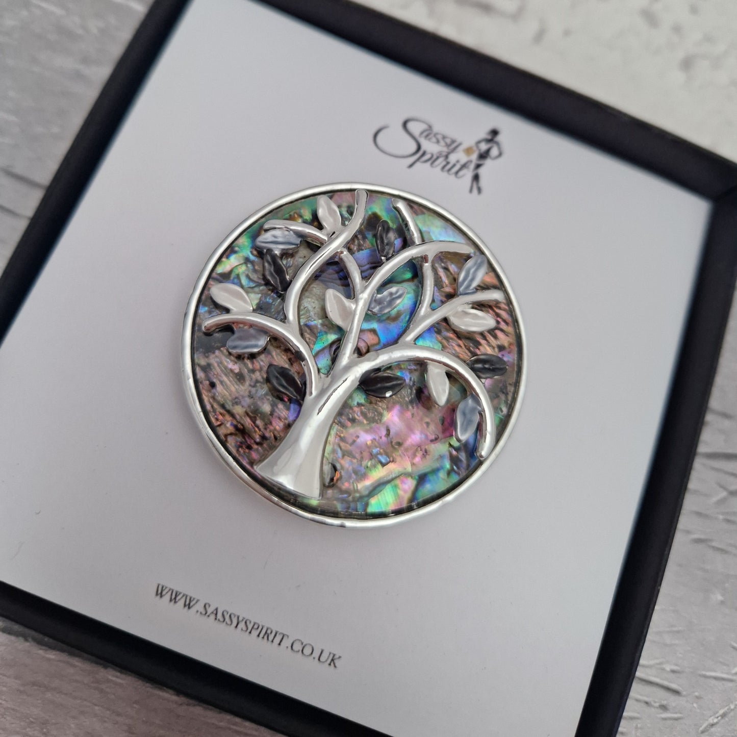 Paua Shell inlaid brooch decorated with a silver tone tree of life. Presented in a Sassy Spirit Gift Box.