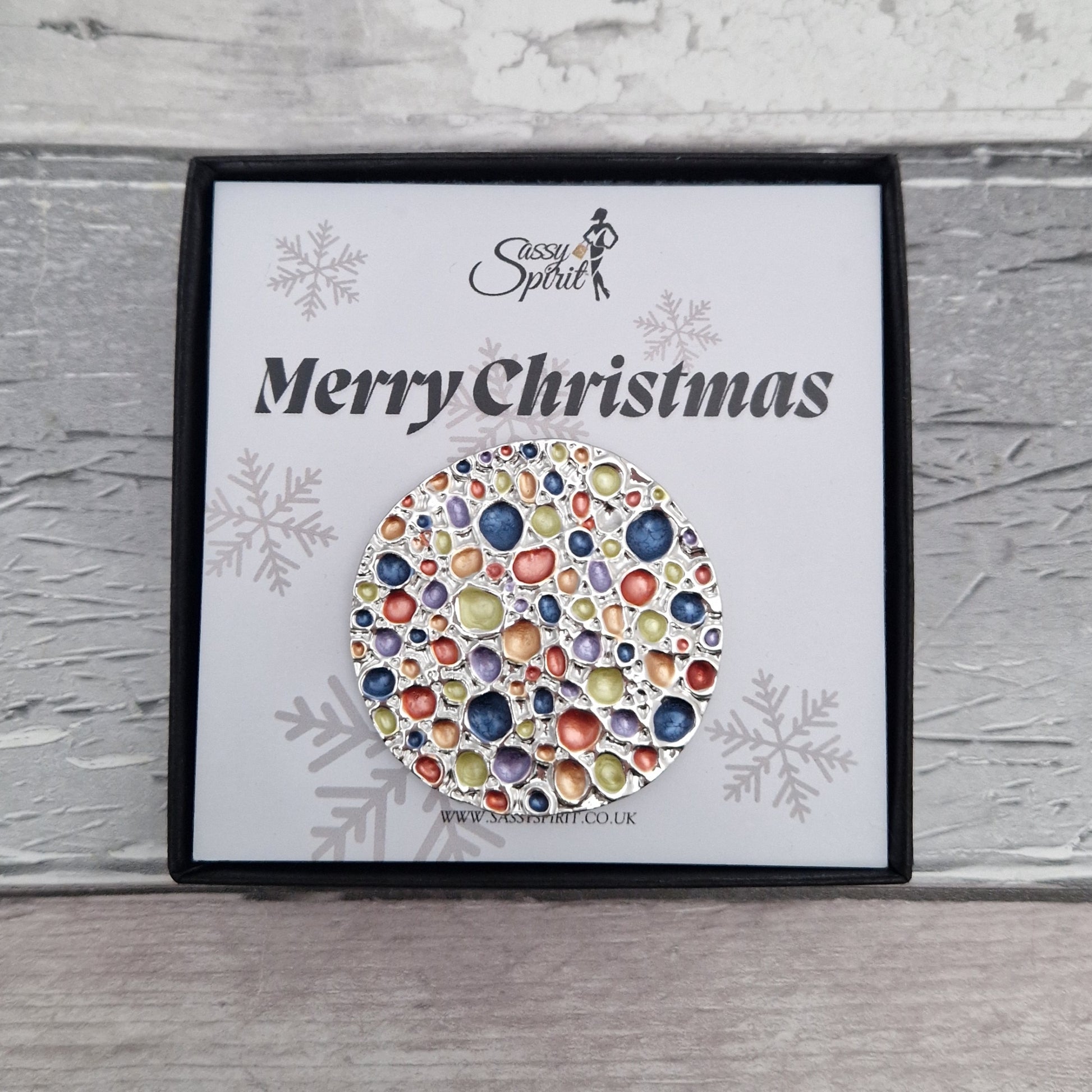 Framed Christmas card with colorful gemstone design and 'Sassy Spirit' branding.