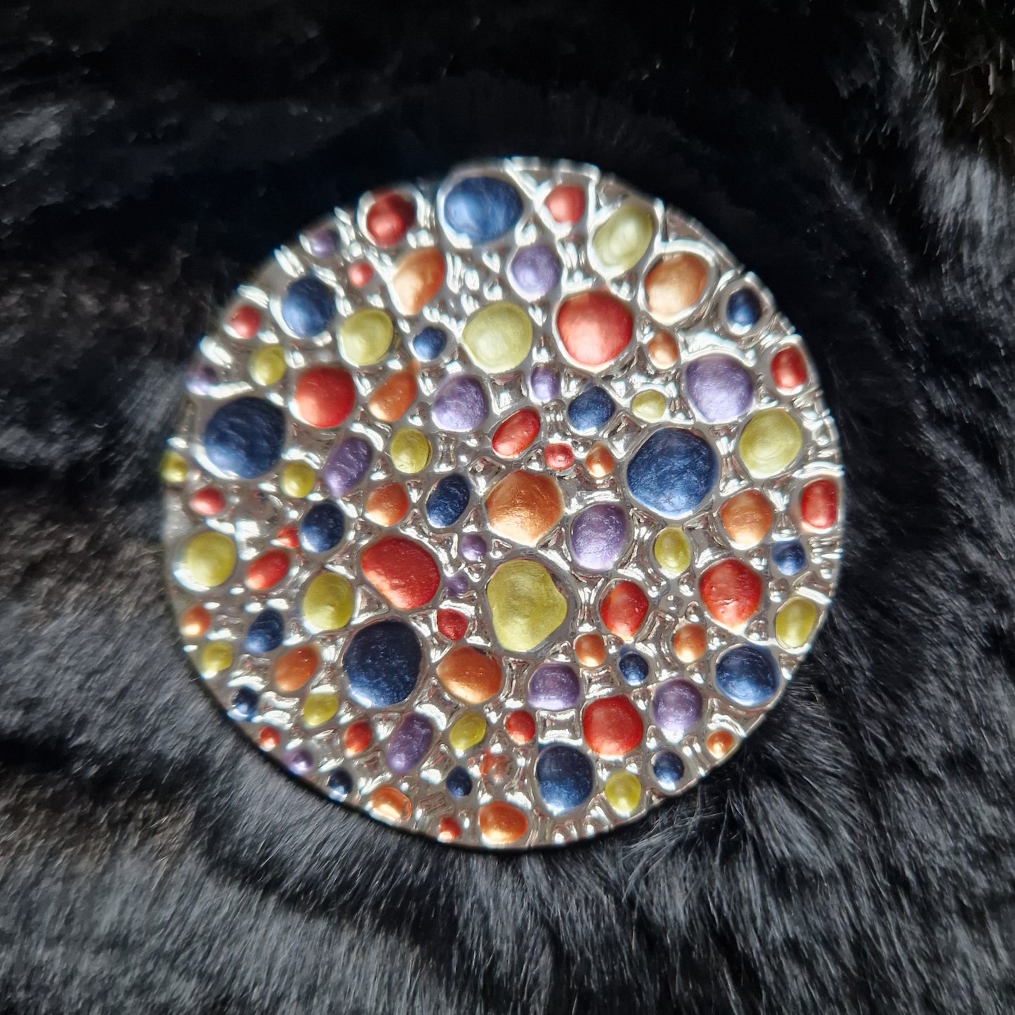 Multicolored circular stone on a black fur background