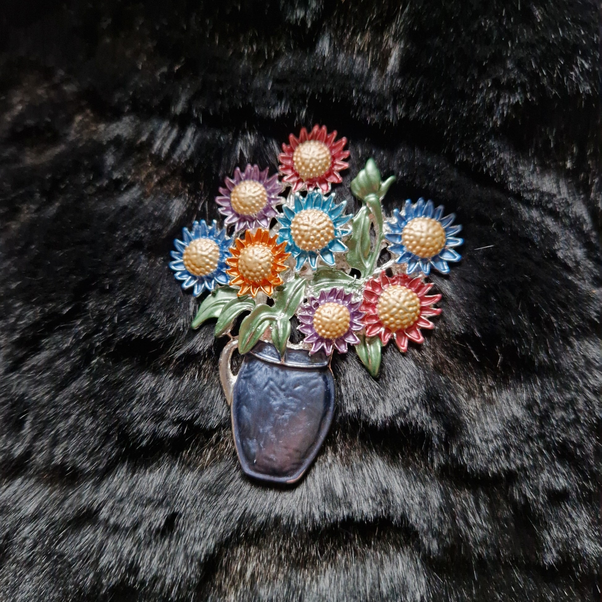 Colorful flower brooch in a vase on black fur background