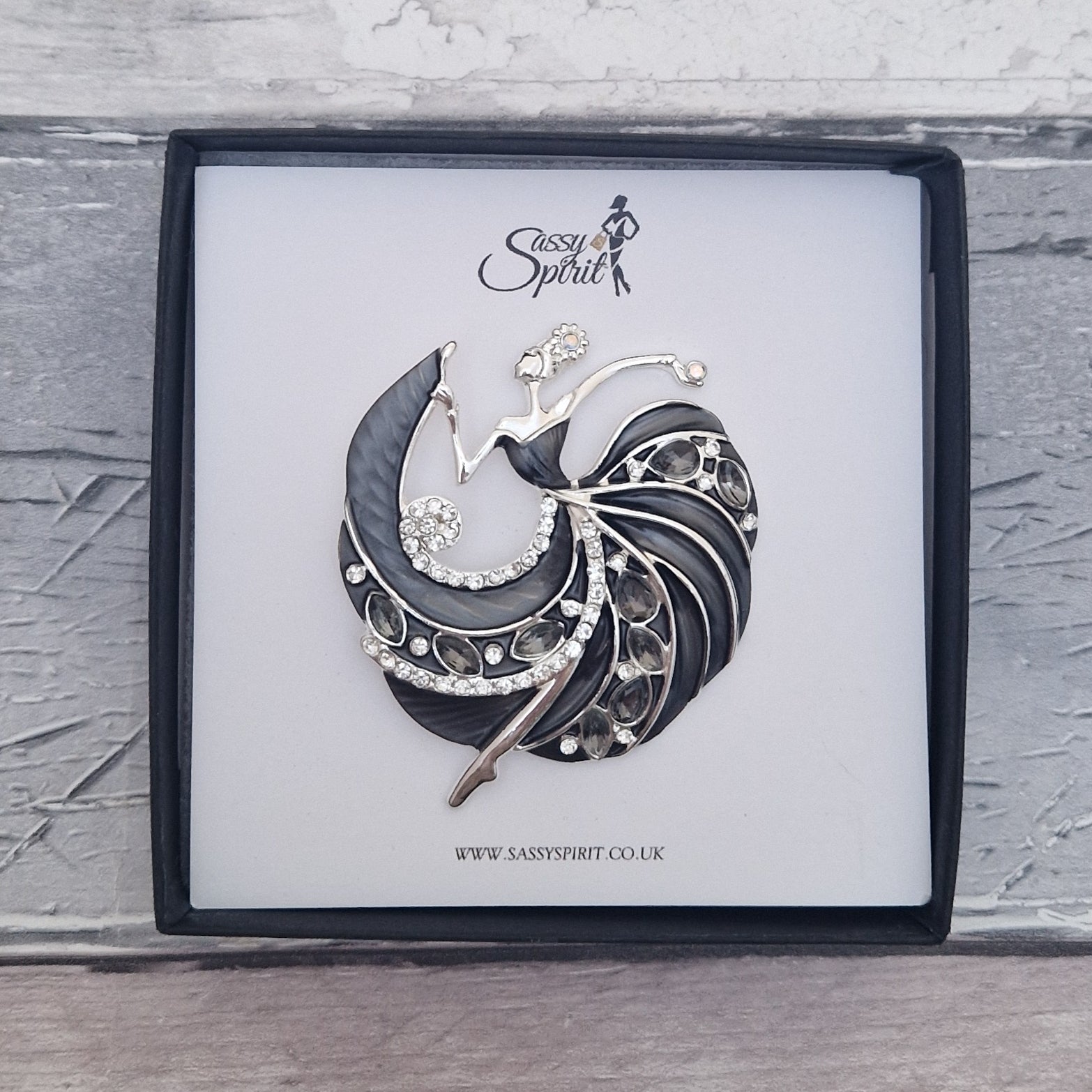 Decorative brooch of a lady in a black gown dancing on a branded display card with 'Sassy Spirit' logo.