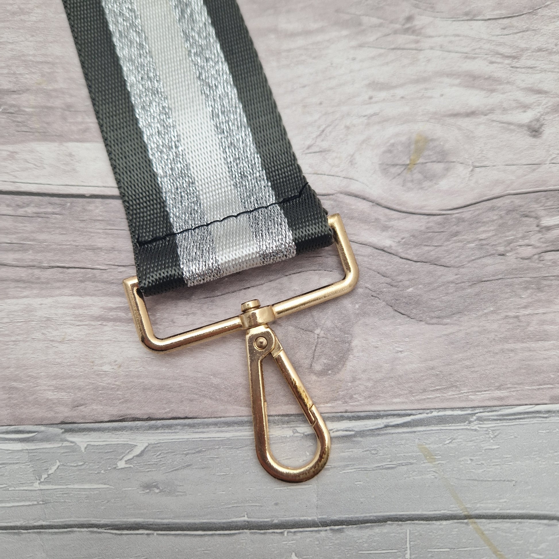 Shades of Dark Grey, white and metallic silver make up this striped Bag strap. Gold metal work.