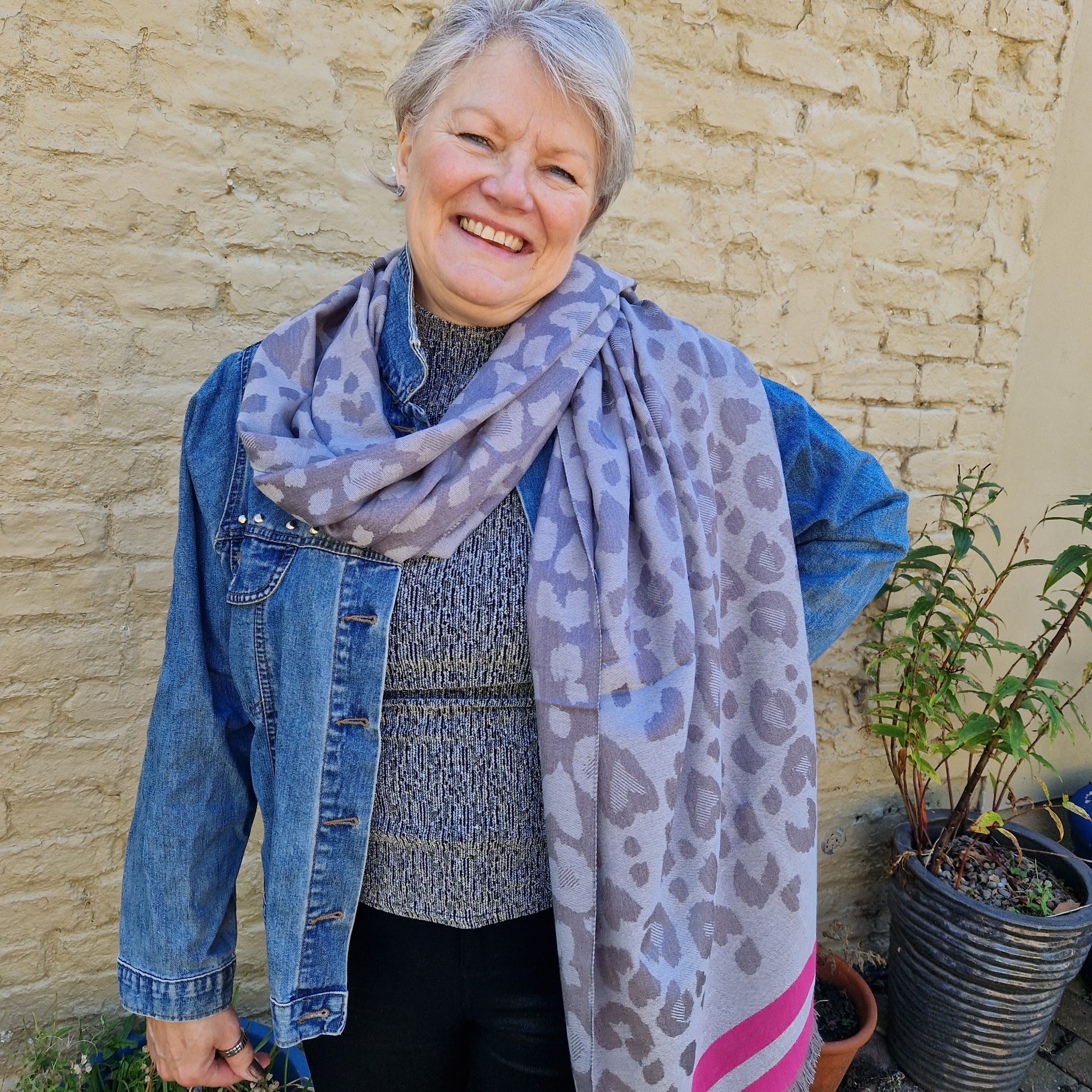 Lady wearing a silver and grey leaopard print scarf with a hot pink coloured trim.