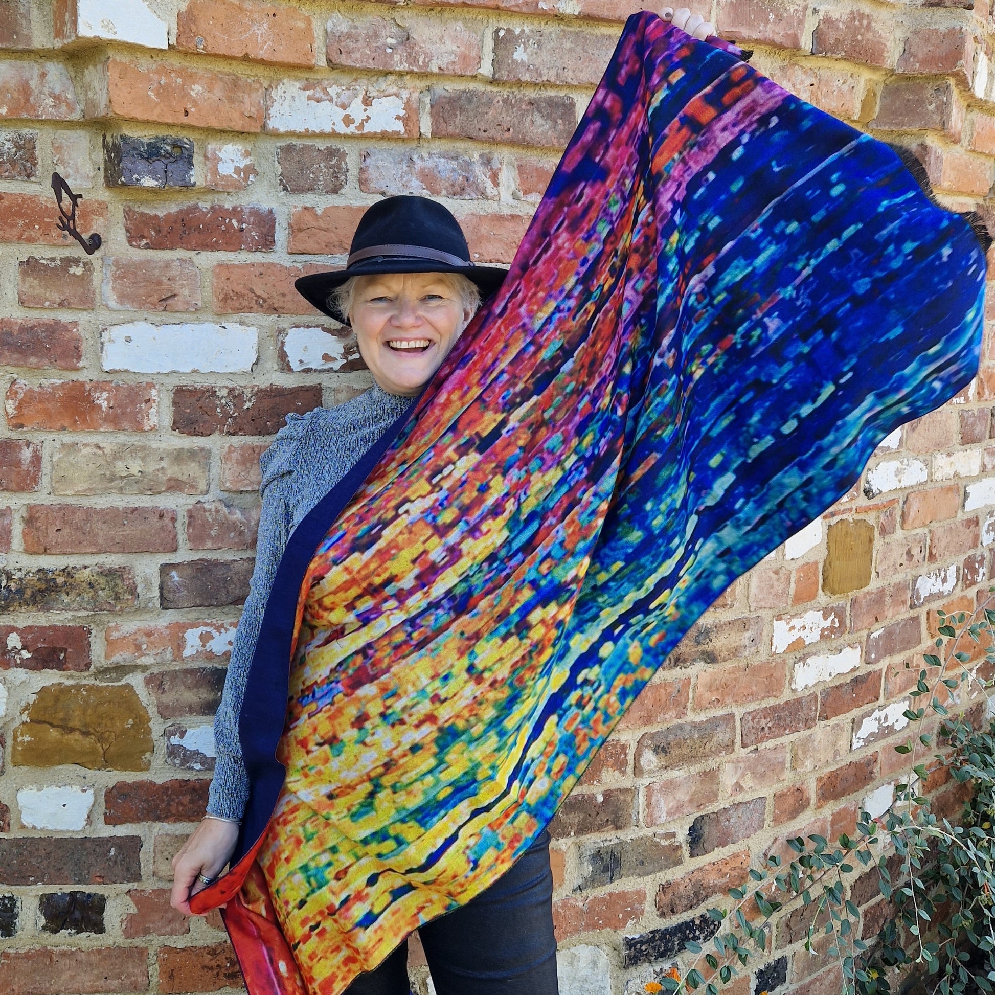 Lady holding up a brightly coloured wrap.