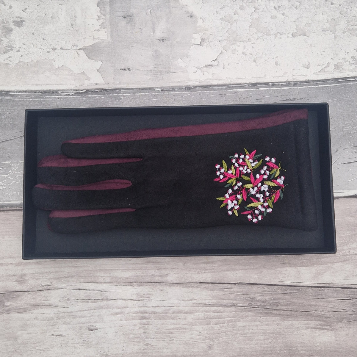 Black gloves with embroidered floral design in presentation gift box.