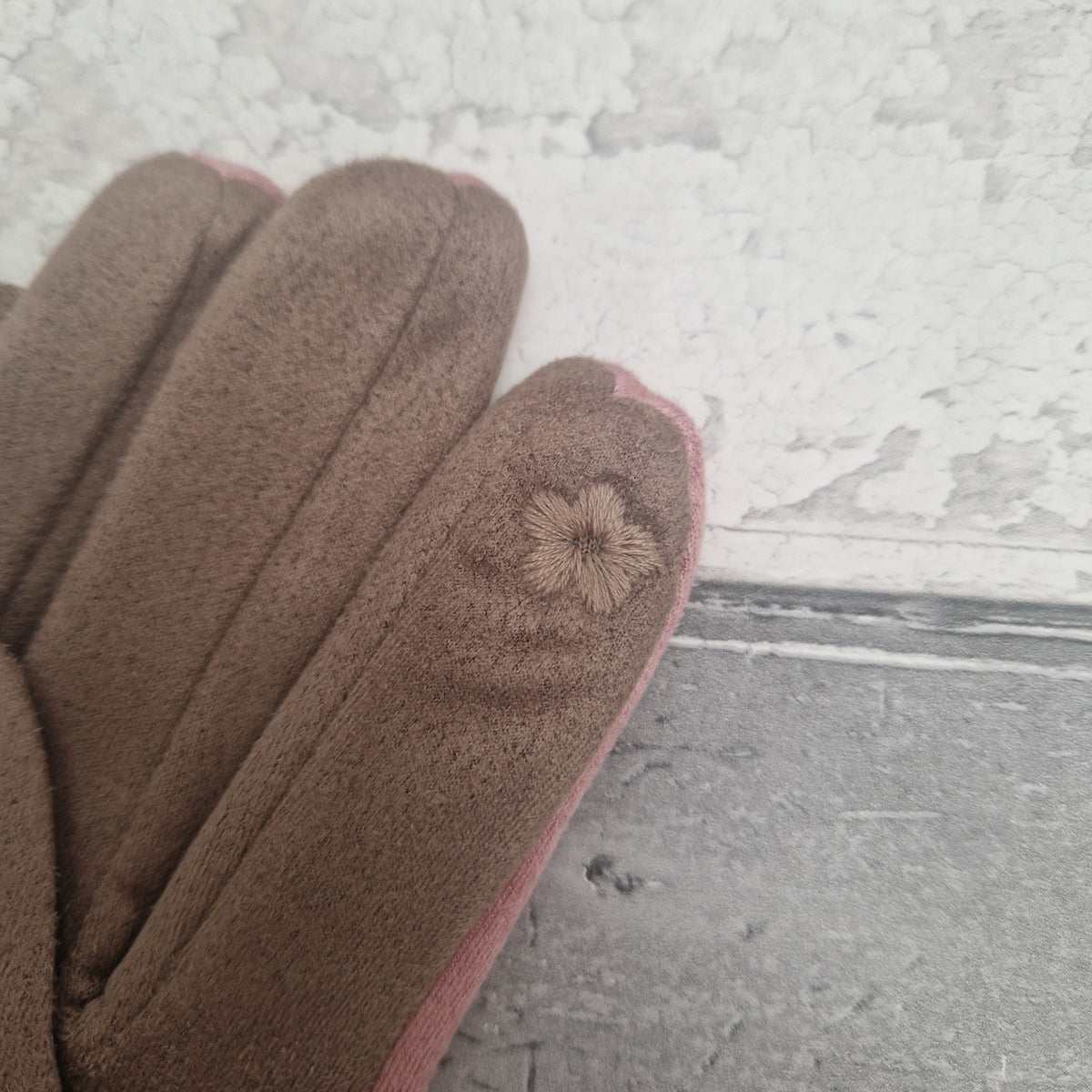Pair of brown gloves with touchscreen finger on a textured surface