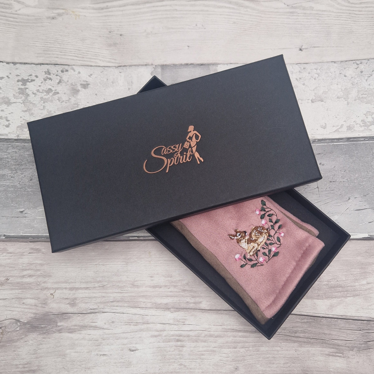 Pink gloves with embroidery in a black box with 'Sassy Spirit' branding on a wooden surface.