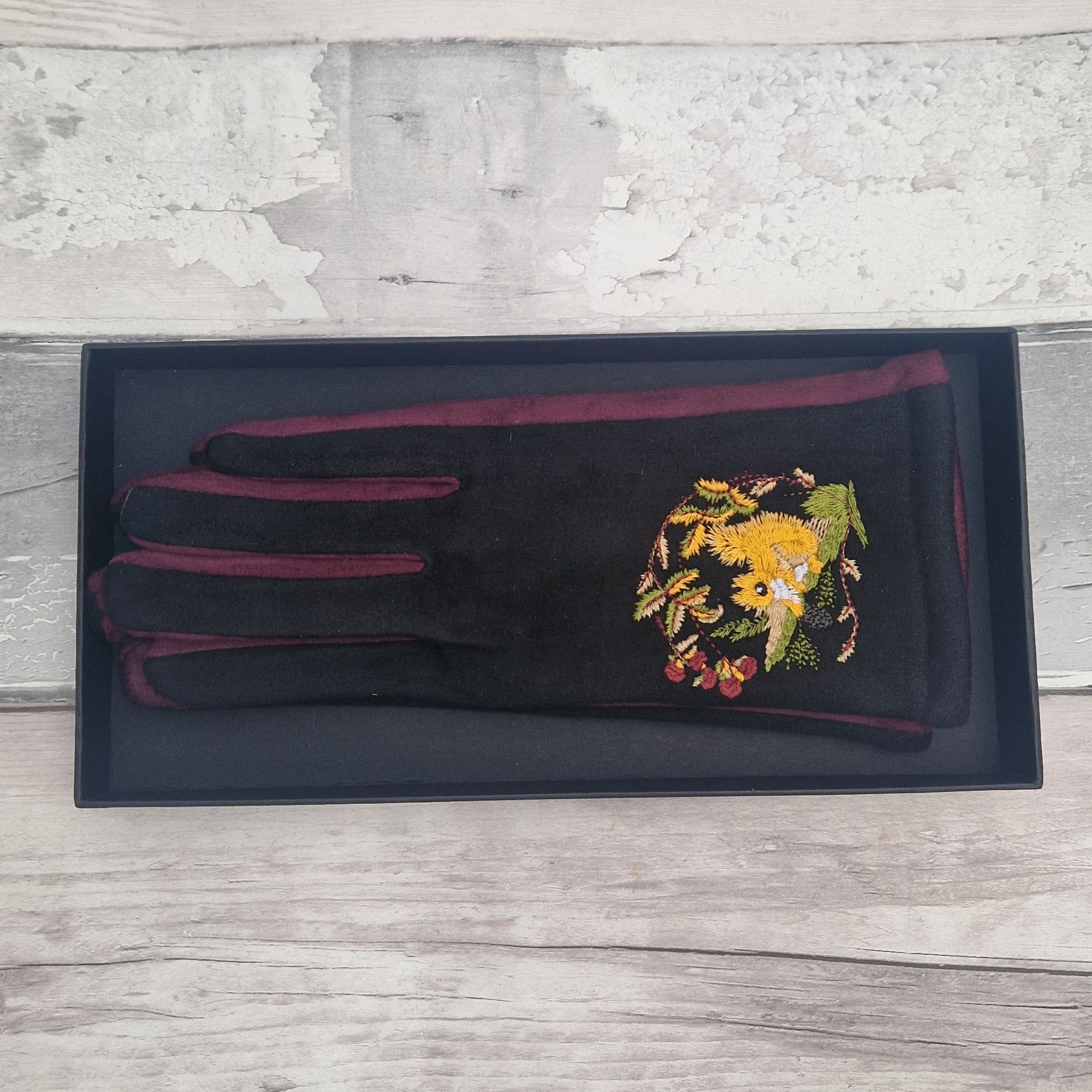 Black gloves with embroidered red squirrel design in presentation gift box.