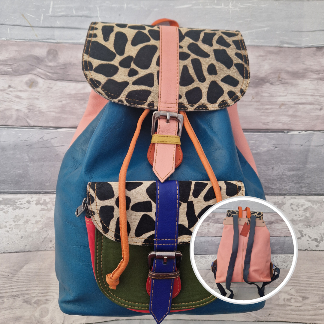 Multicolored backpack made from leather with front pocket and magnetic buckle closers. Pink and blue colours with textured giraffe print panels.