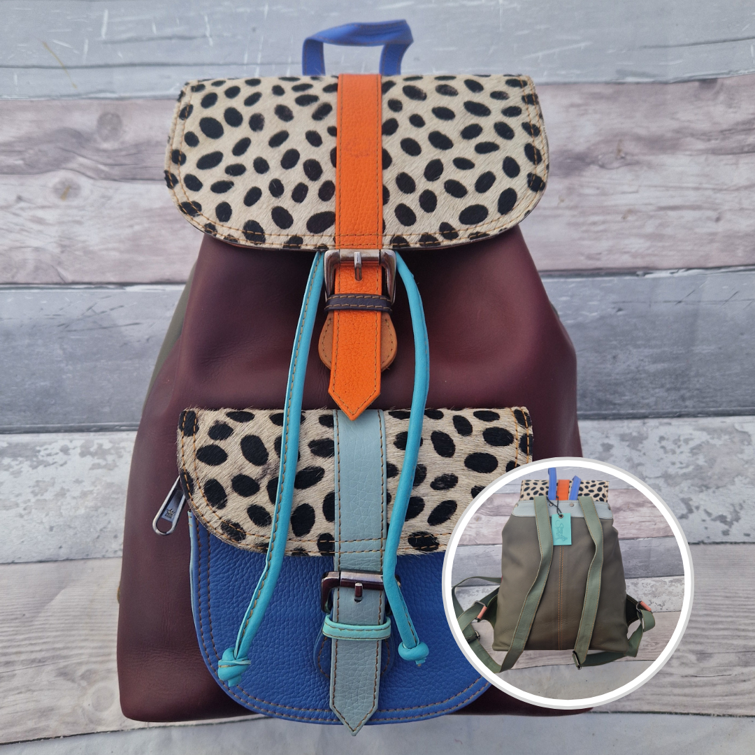 Multicolored backpack made from leather with front pocket and magnetic buckle closers. Burgundy and blue colours with textured spot print panels.