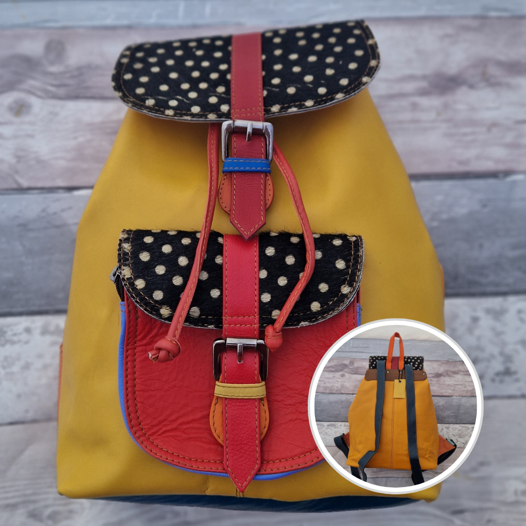 Multicolored backpack made from leather with front pocket and magnetic buckle closers. Sunshine yellow, blue and red colours with textured panels of black and white spots.