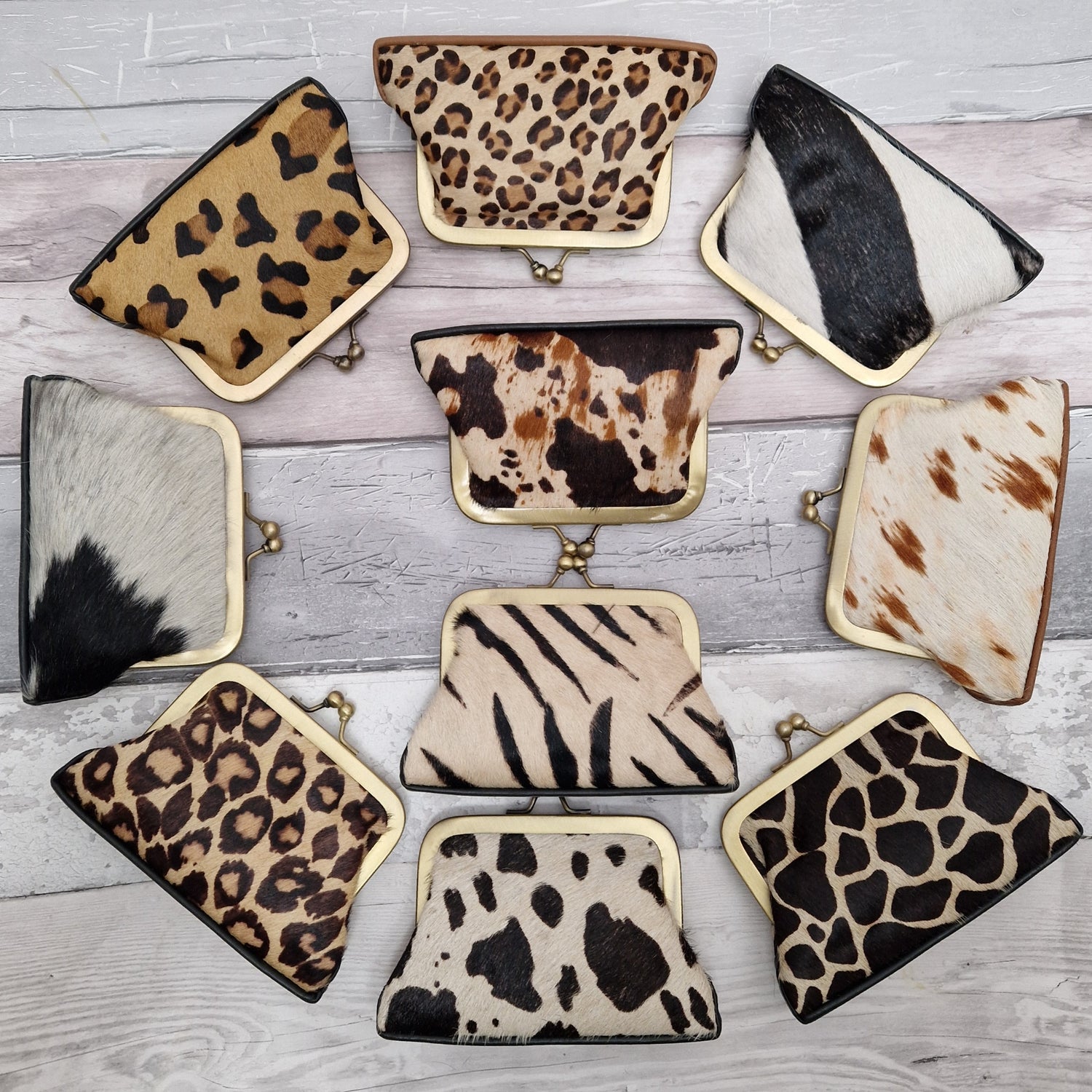 10 Animal print purses set out in a wheel shape; leopard, zebra, panda, cow, pony, giraffe, jaguar prints.
