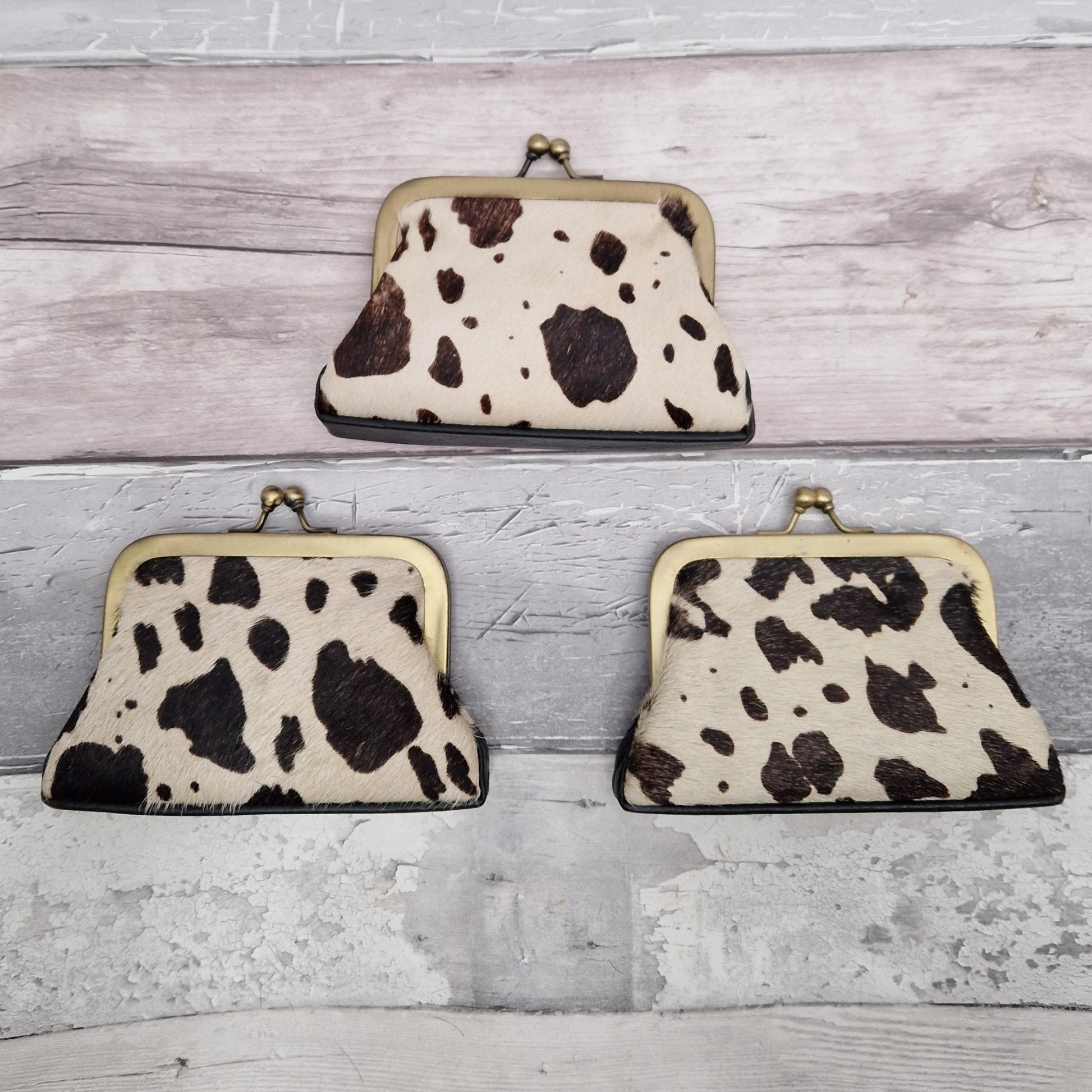Vintage inspired coin purses with a metal frame and twist lock finished in textured black and white cow print.