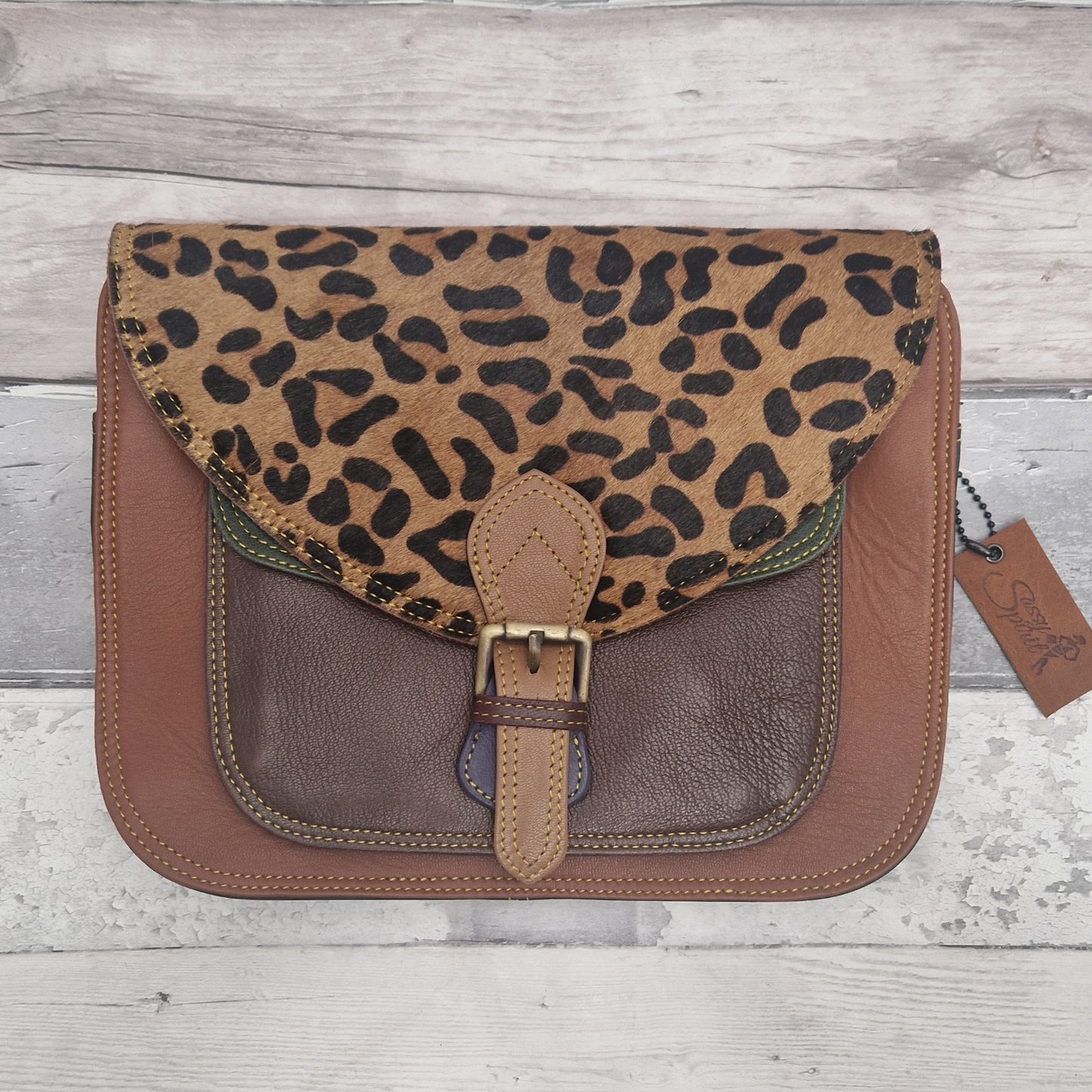 Leopard print and brown leather bag on a wooden surface