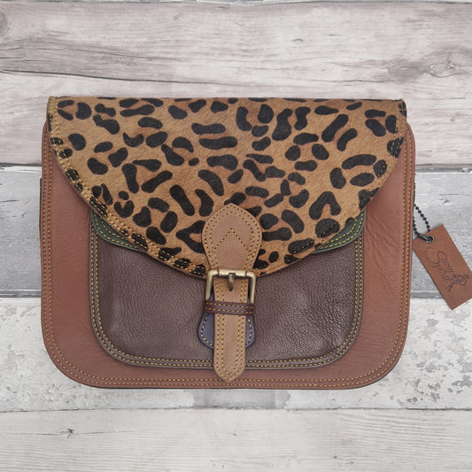 Leopard print and brown leather bag on a wooden surface