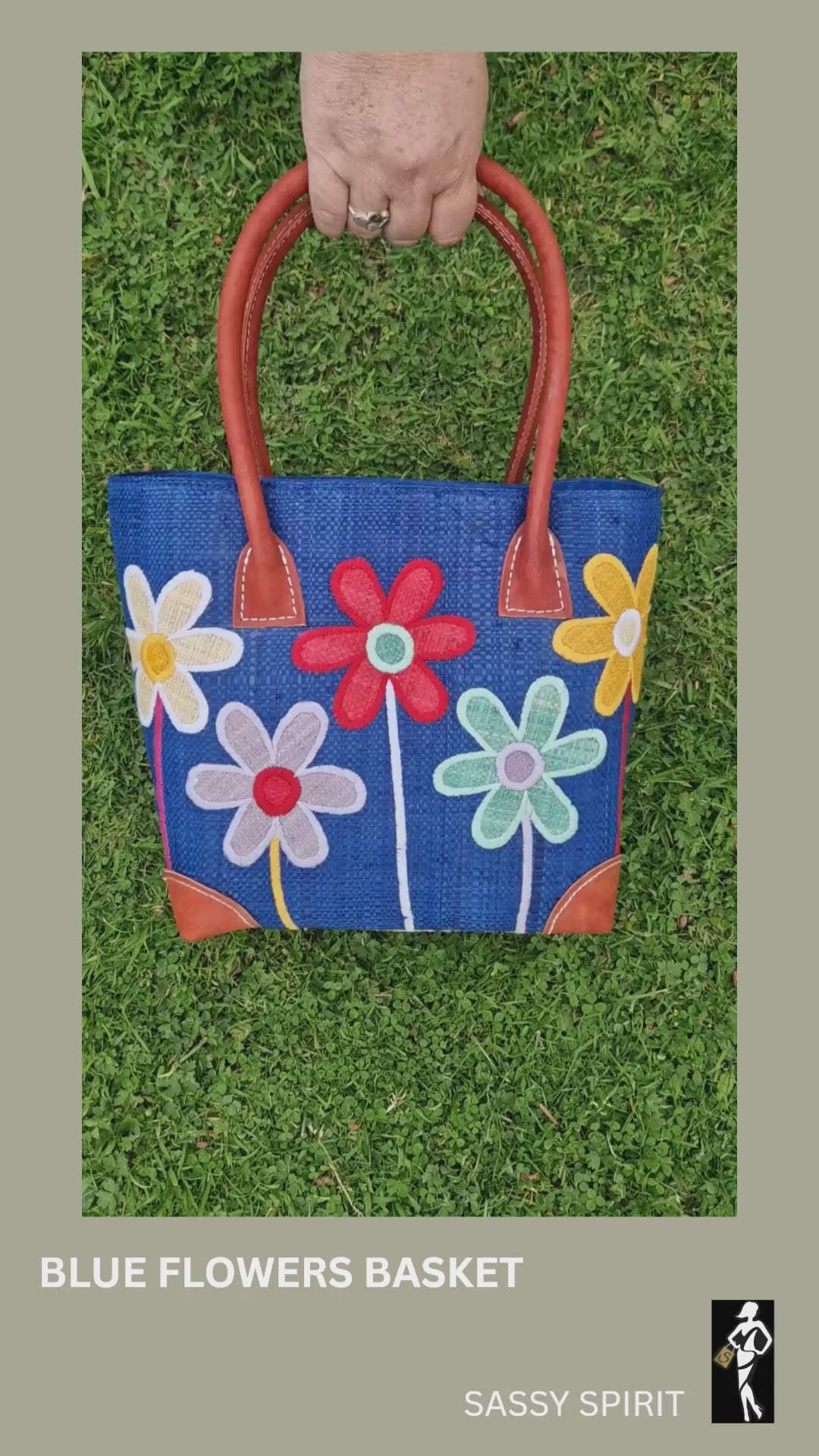 Blue raffia basket bag decorated with long stemmed flowers in a mix of colours. Drawstring top demonstration.
