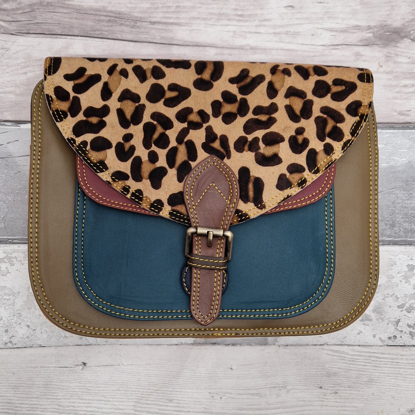 Large Saddlebag style leather crossbody bag. Multicoloured panels of olive green, turquoise and red finished with a leopard print textured flap.