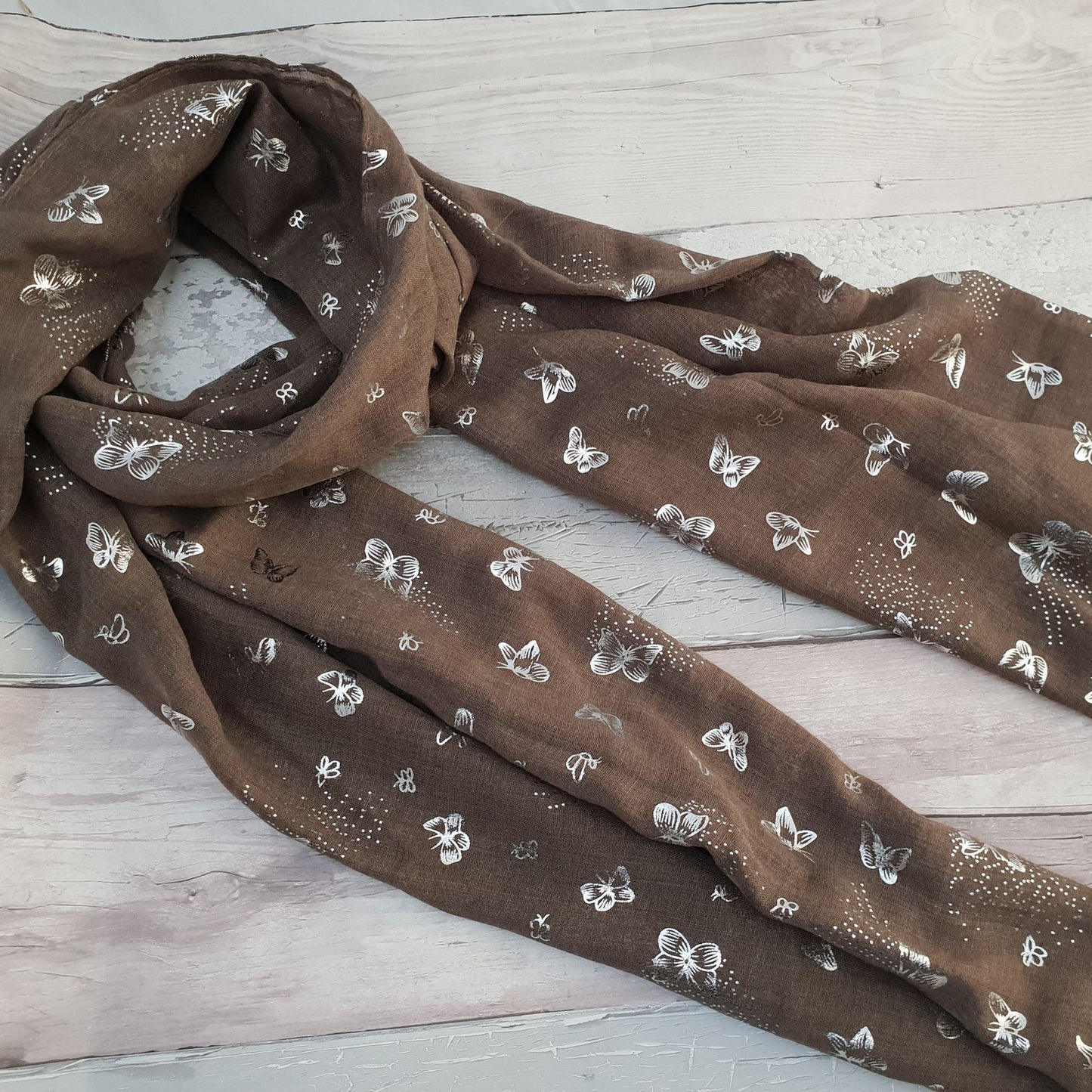 Photo of khaki coloured scarf covered in metallic Silver butterflies