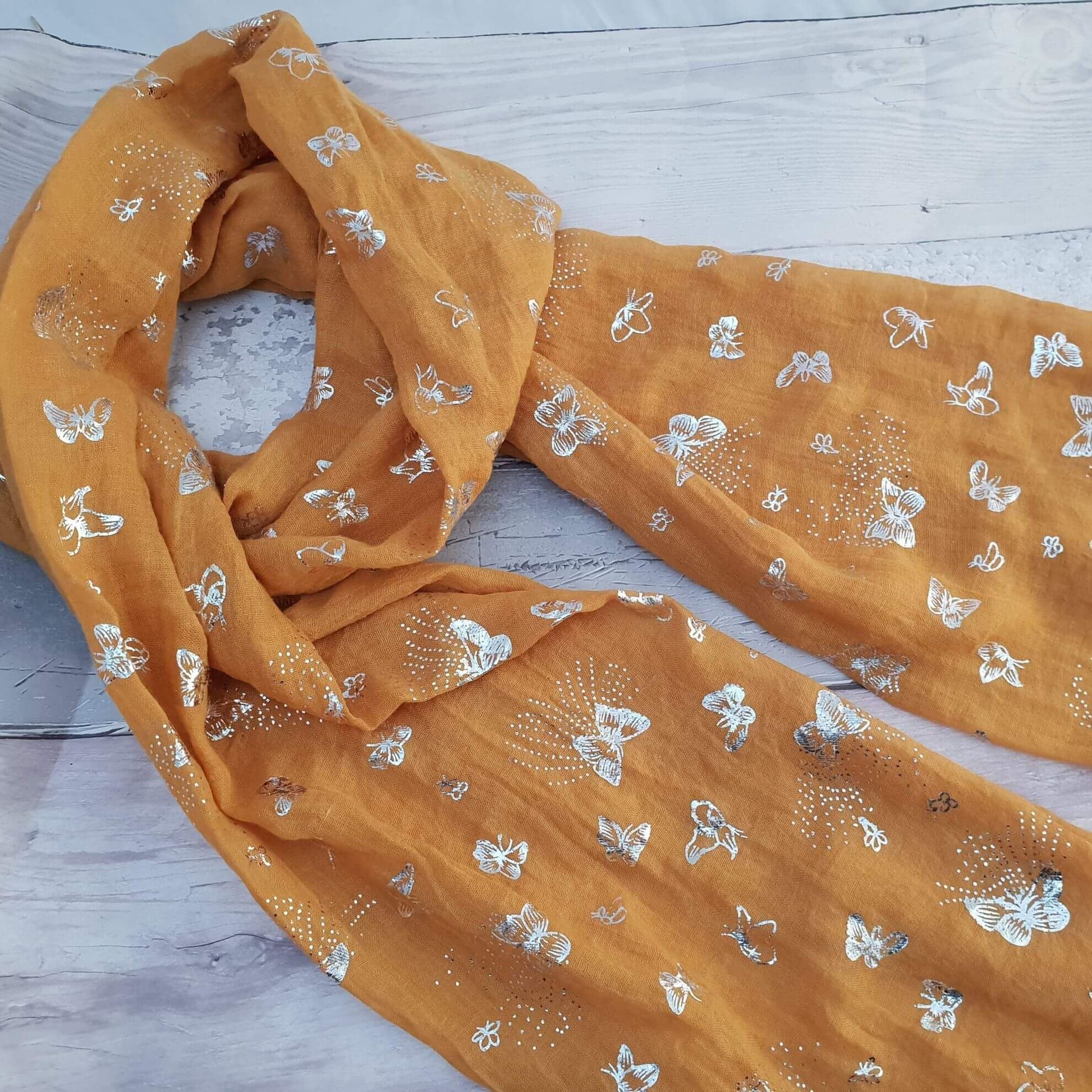 Photo of a Mustard coloured scarf decorated with silver butterflies