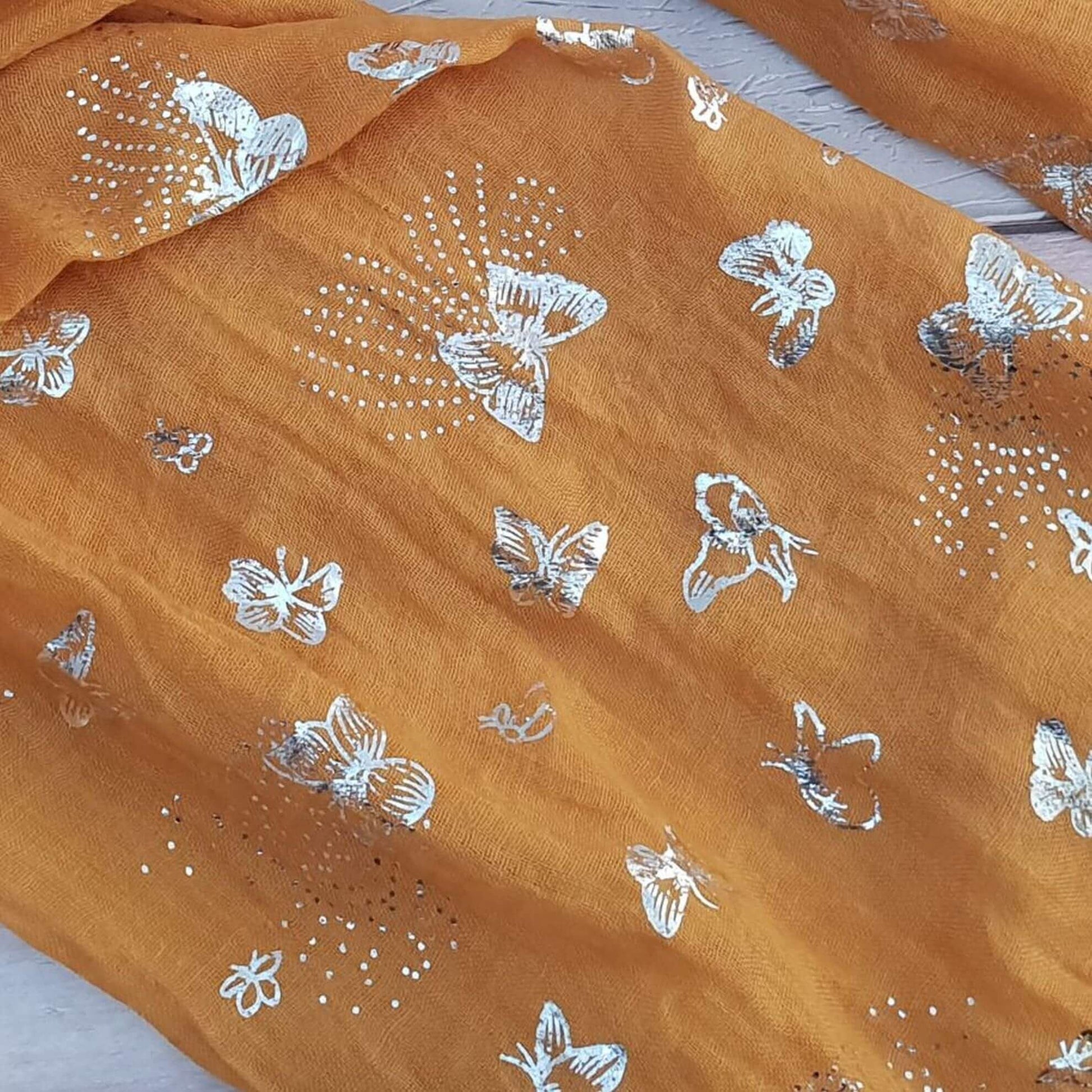 Photo of a Mustard coloured scarf decorated with silver butterflies