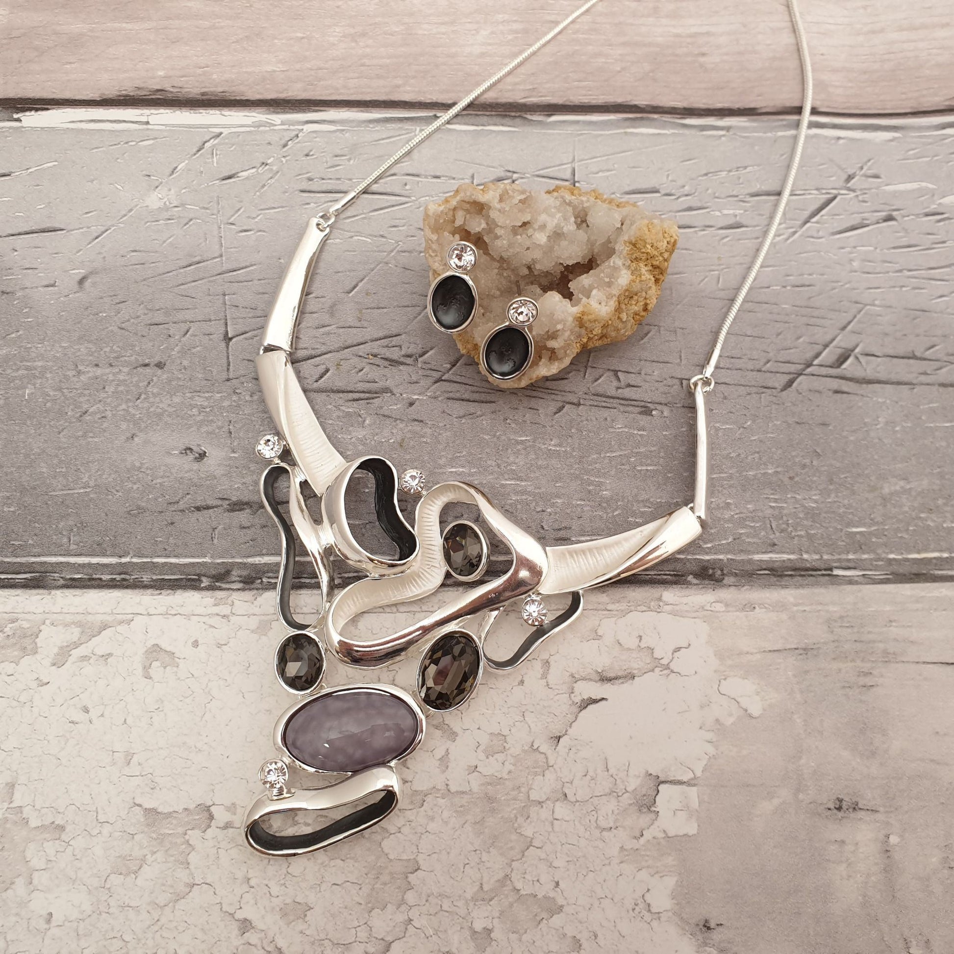 Photo of a statement necklace in silver and grey tones with matching earrings