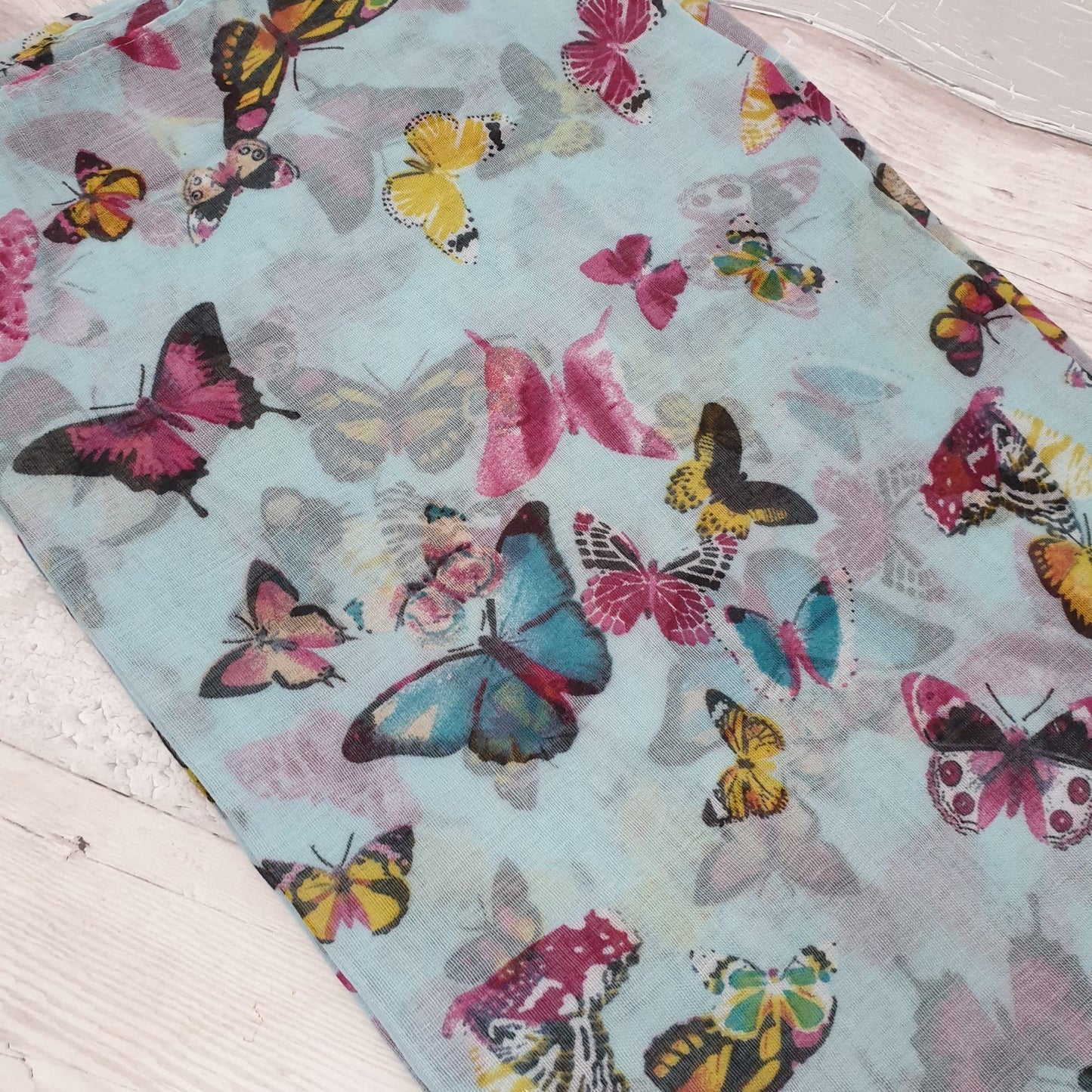Photo of a Turquoise scarf covered in pink butterflies