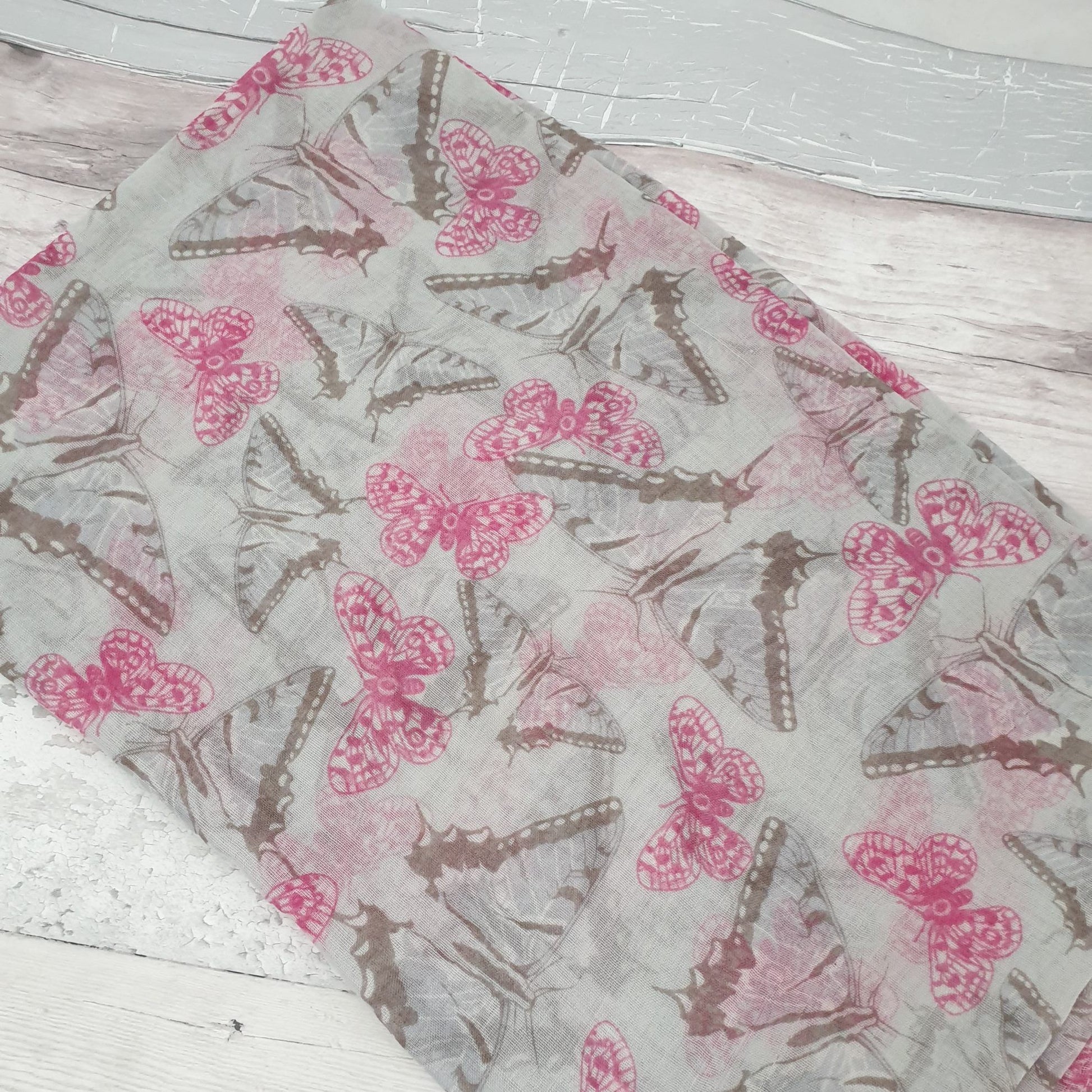 Photo of a light grey scarf covered in pink and monochrome butterflies