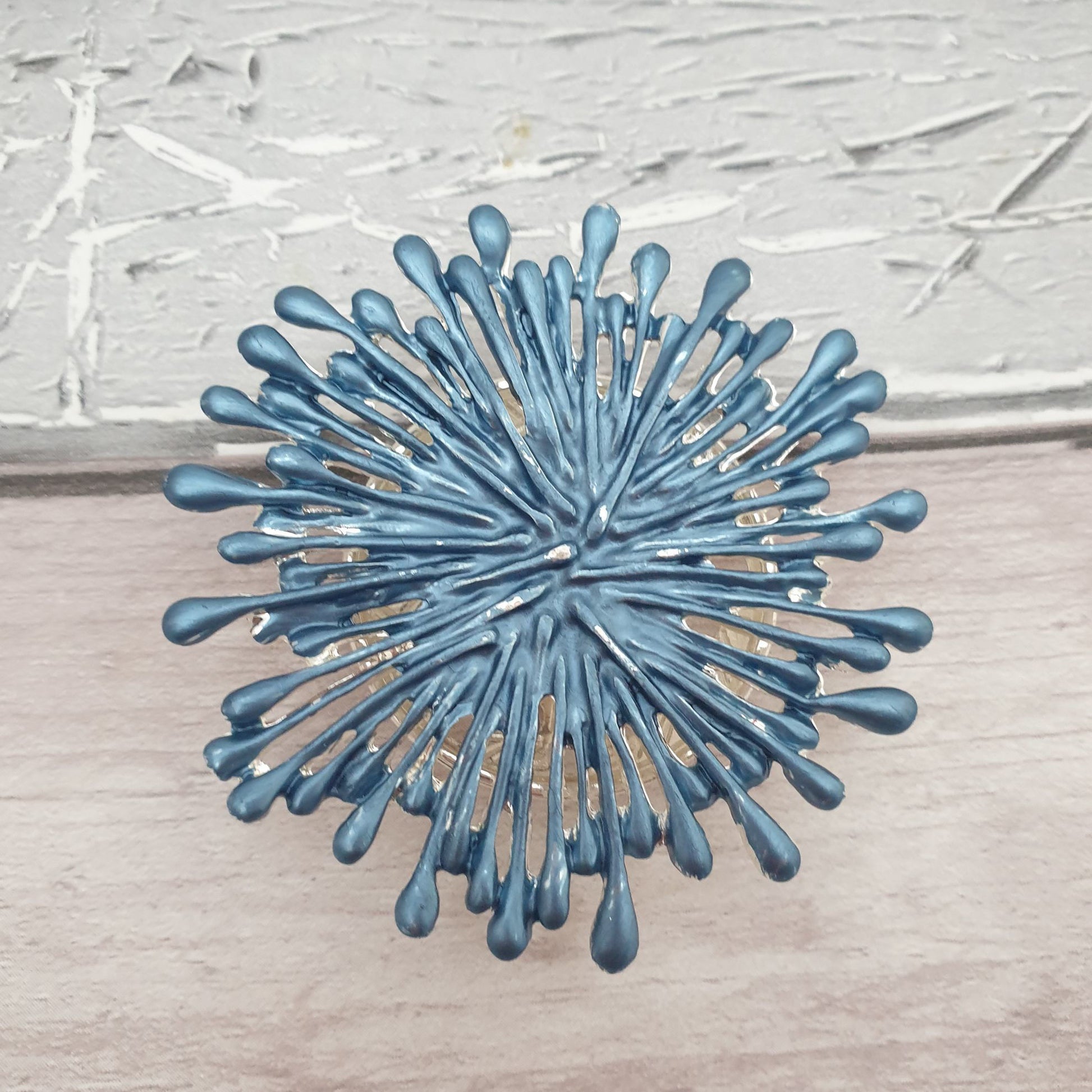 Photo of a blue brooch shaped like a firework explosion