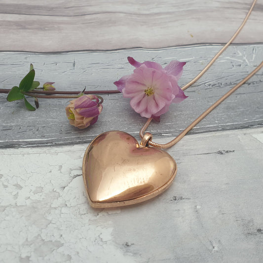 Photo of a solid rose gold love heart pendant on a long necklace