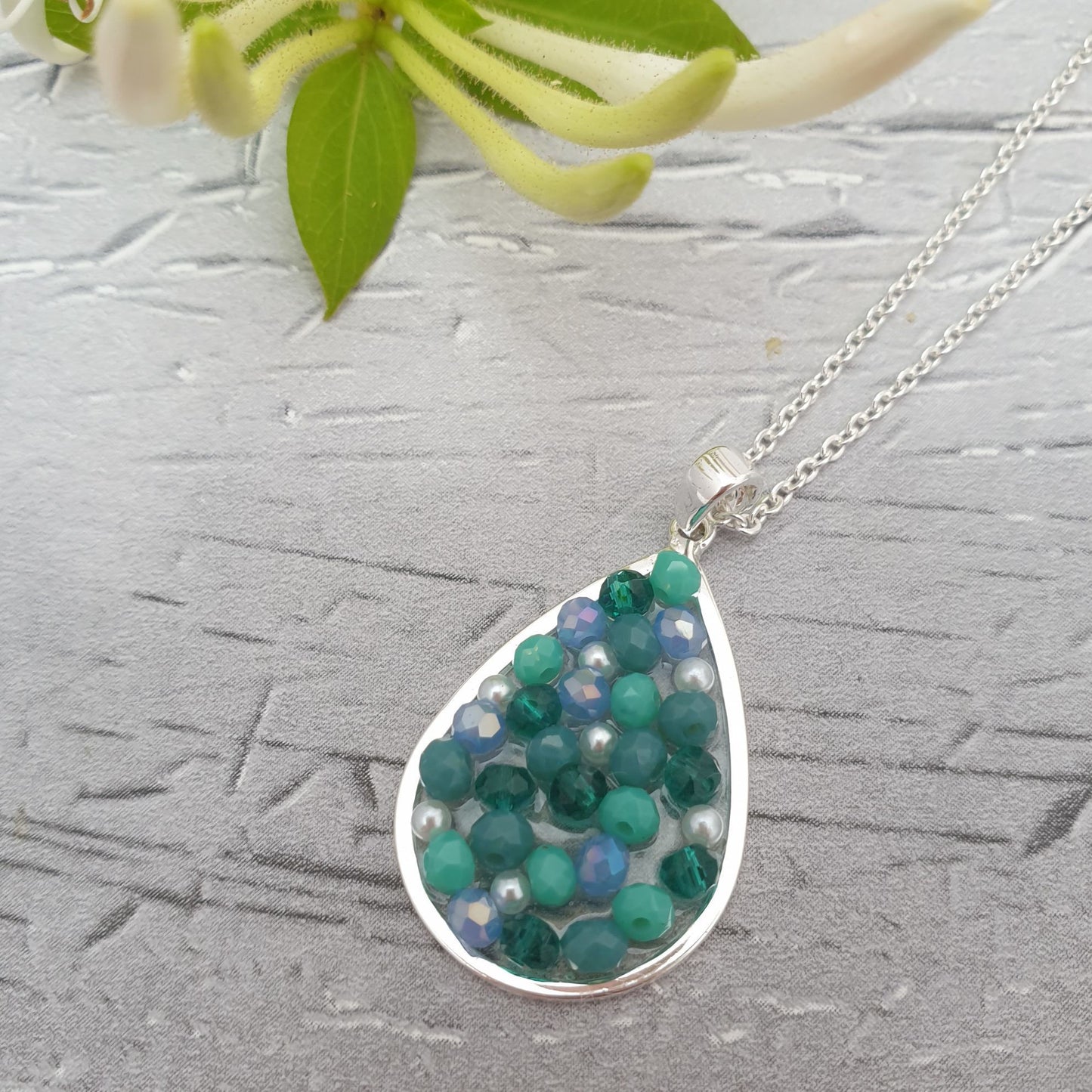 Photo of a Teardrop shaped  pendant necklace decorated with pearls, turquoise crystals and beads