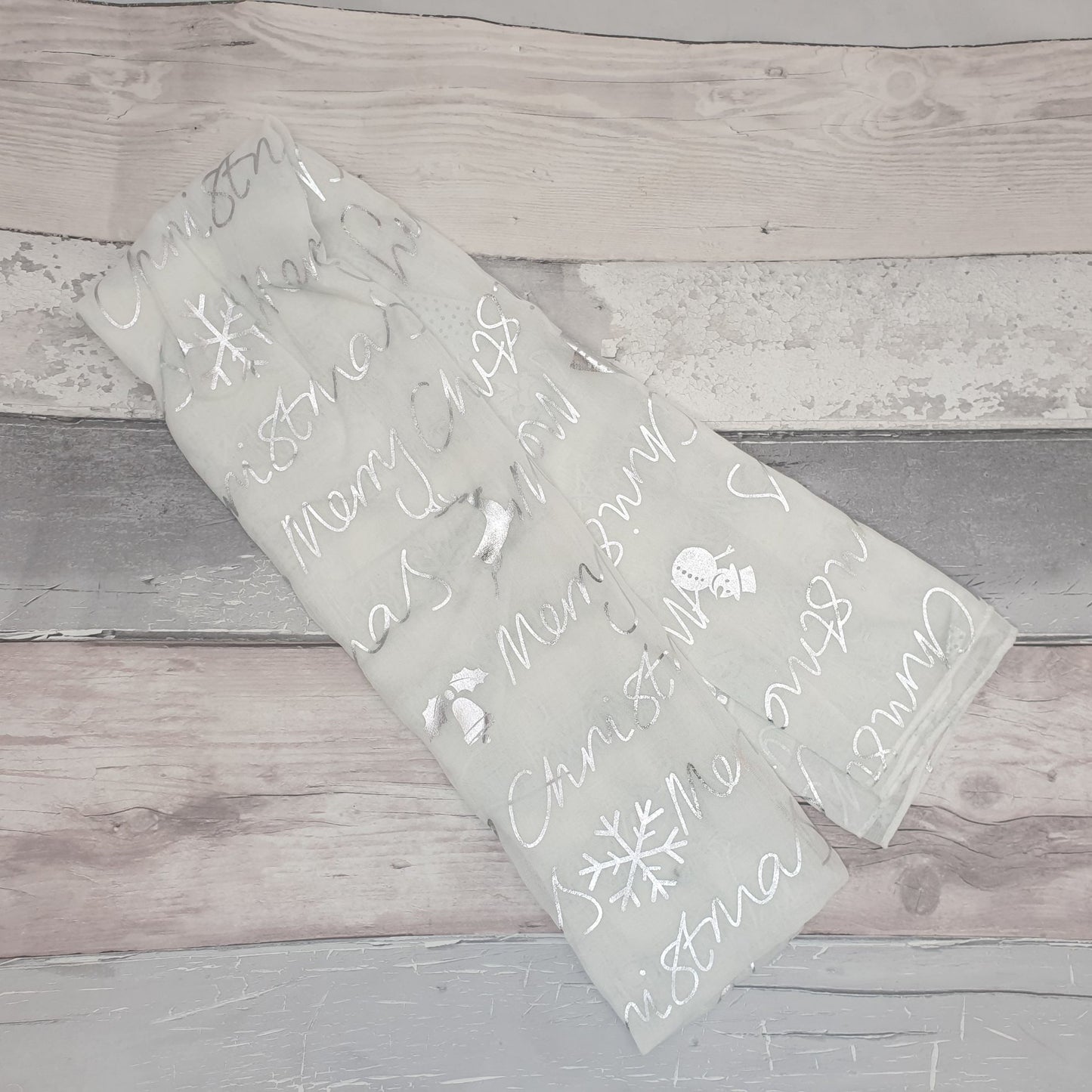 Photo of a white scarf decorated in silver with Christmas symbols