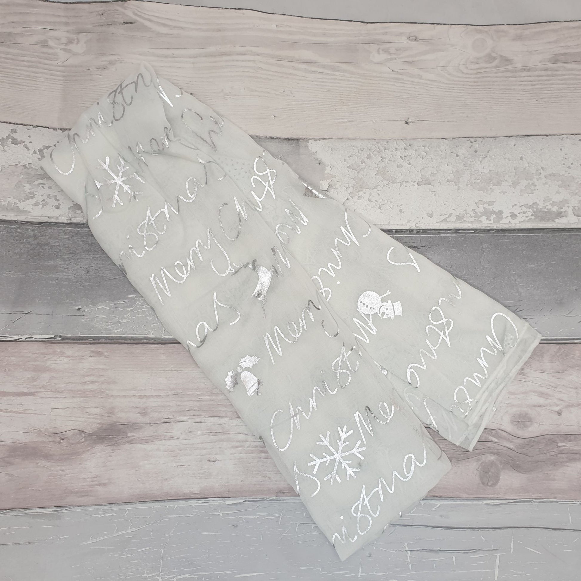 Photo of a white scarf decorated in silver with Christmas symbols
