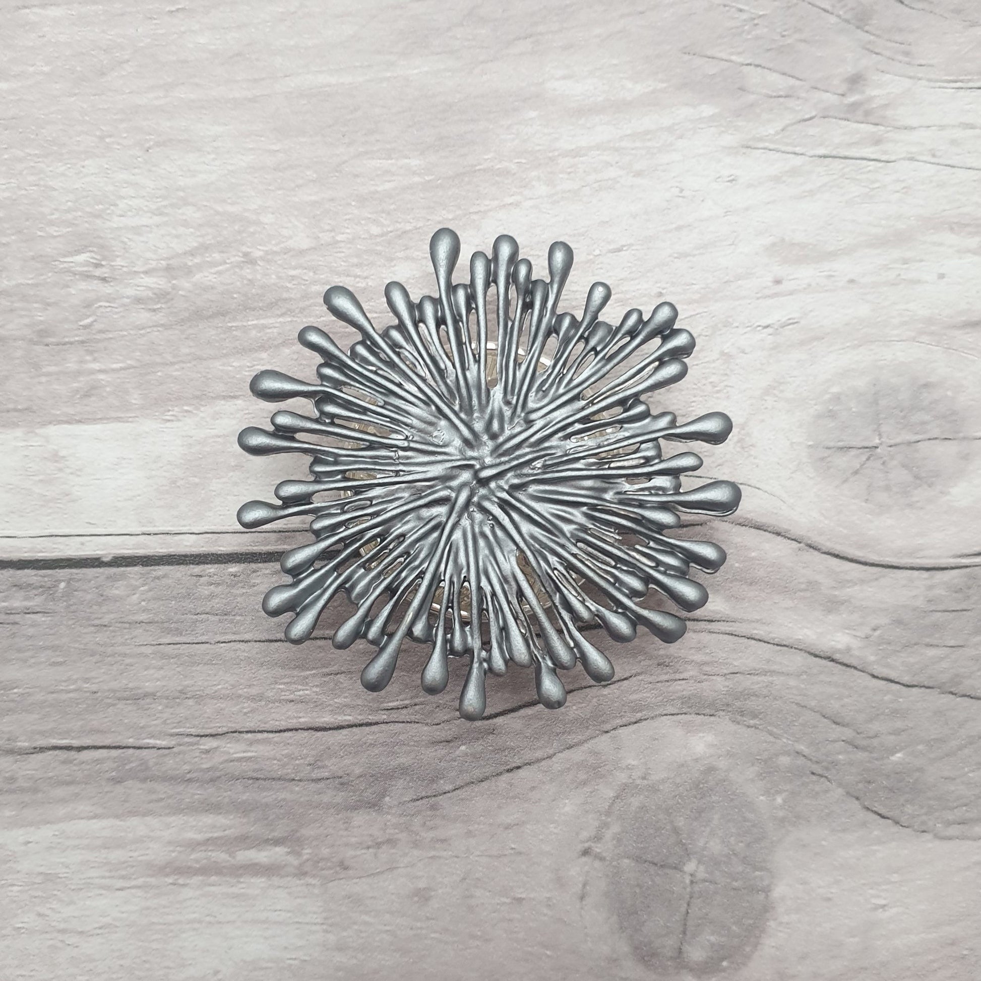 Photo a brooch that looks like an exploding grey firework
