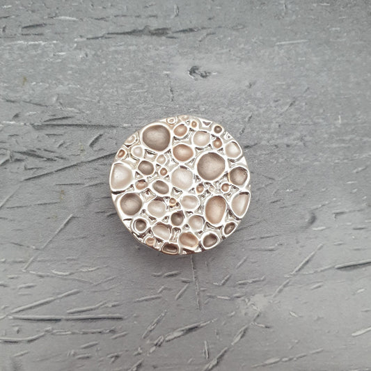 Photo of a magnetic brooch with a beige pebble design