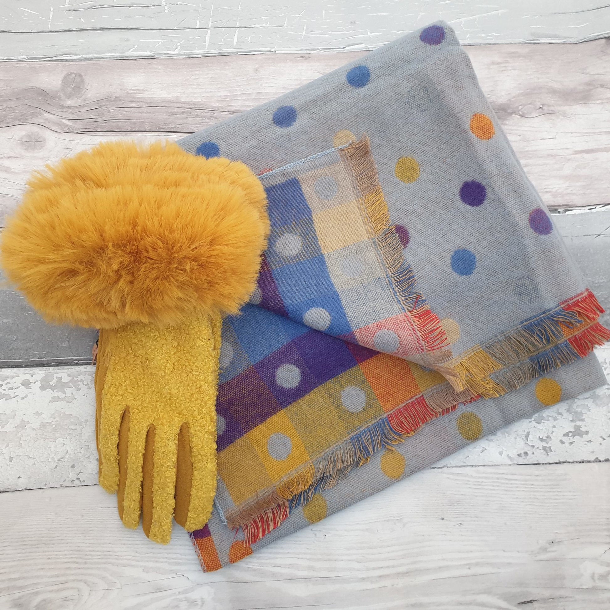 Photo of a blue scarf with rainbow coloured spots with mustard yellow ladies gloves