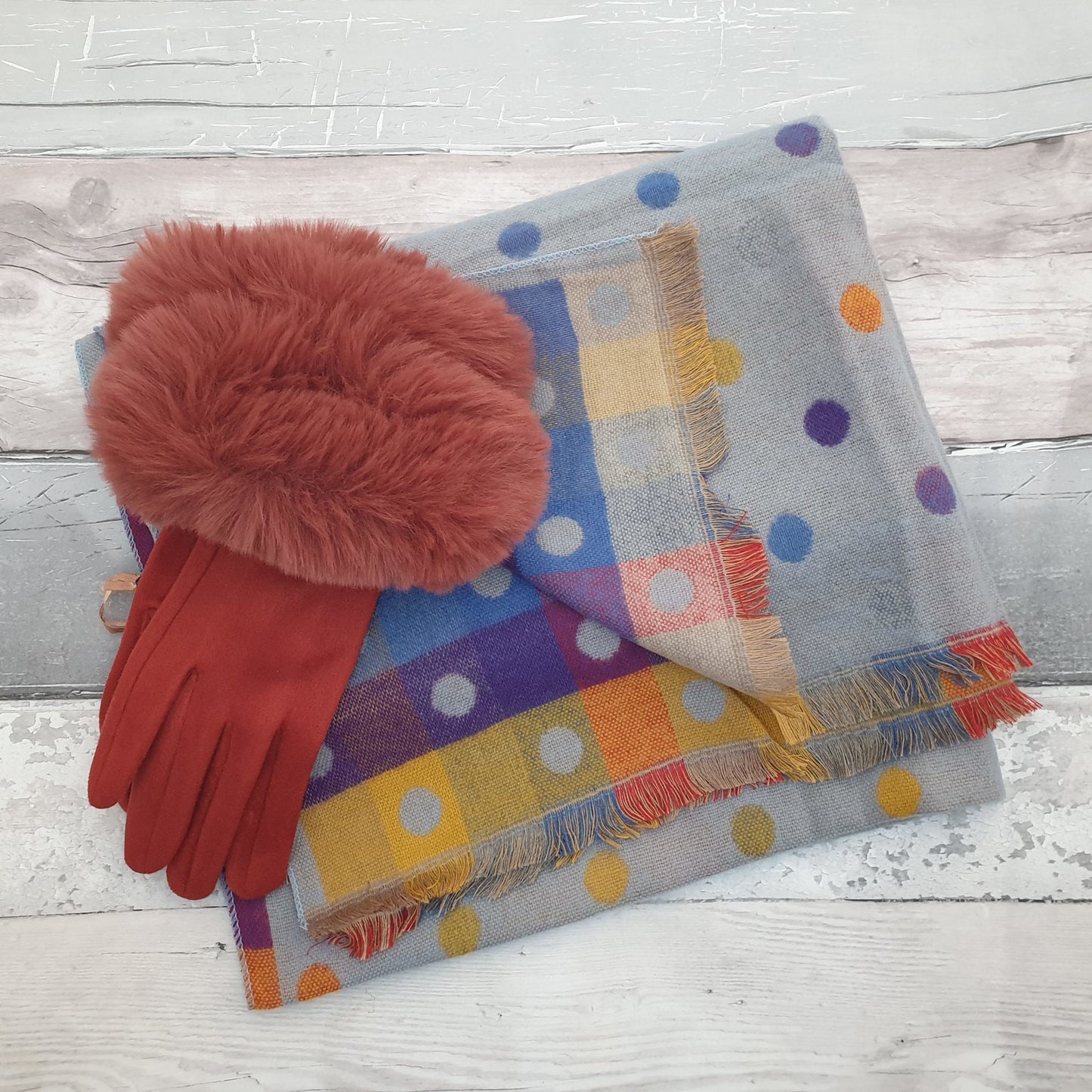 Photo of a blue scarf with rainbow coloured spots with rust coloured ladies gloves