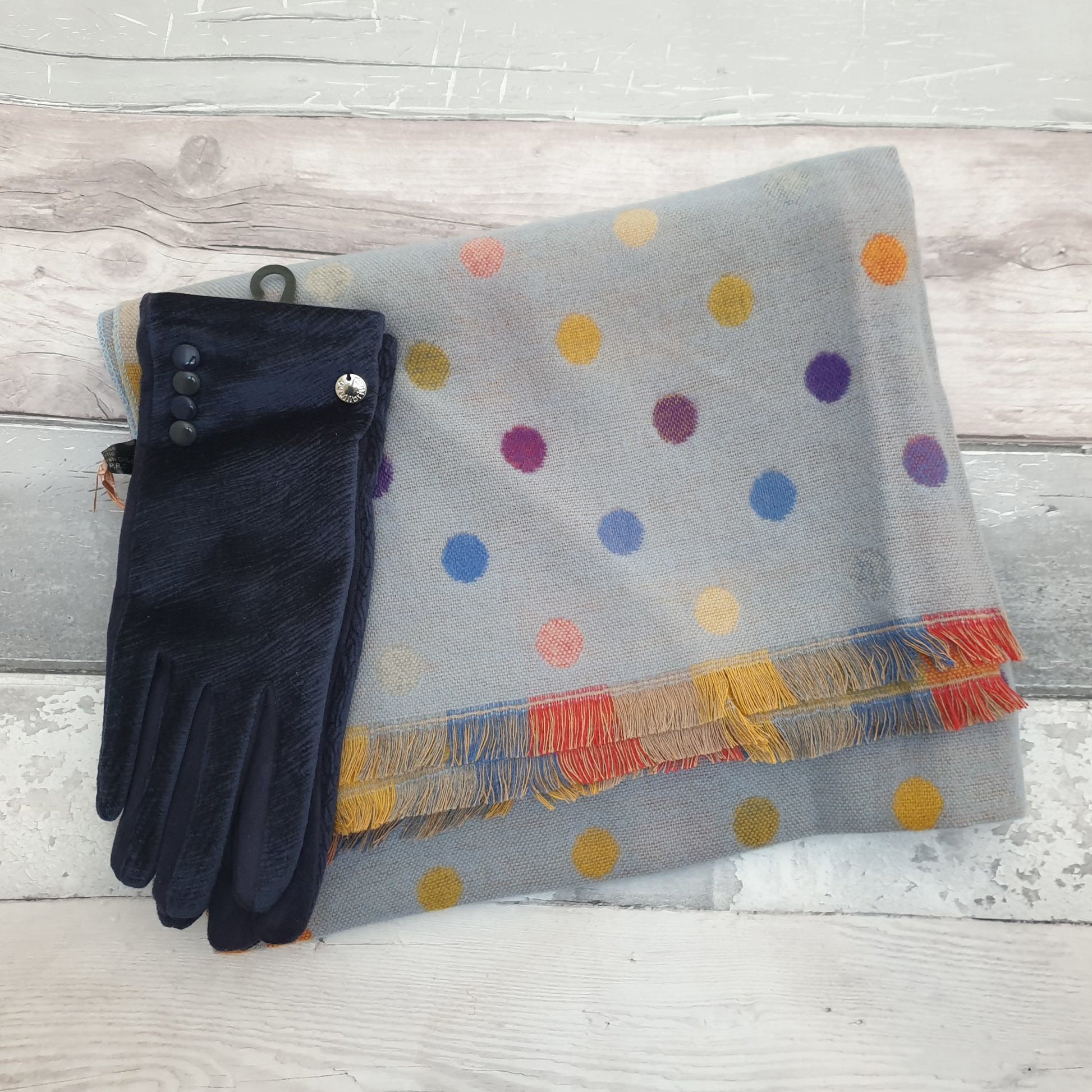 Photo of a blue scarf with rainbow coloured spots with navy coloured ladies gloves