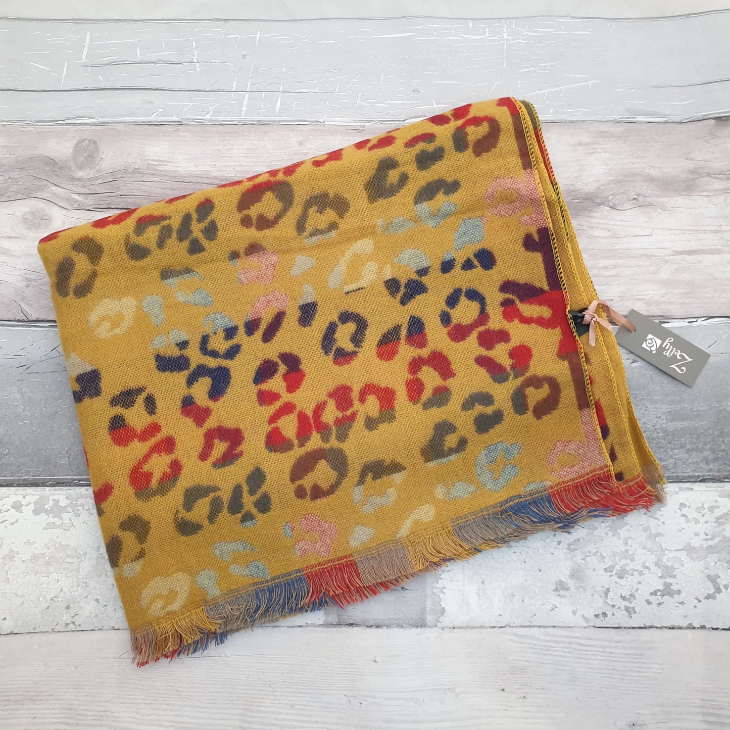 Photo of a mustard coloured animal print scarf with rainbow colours