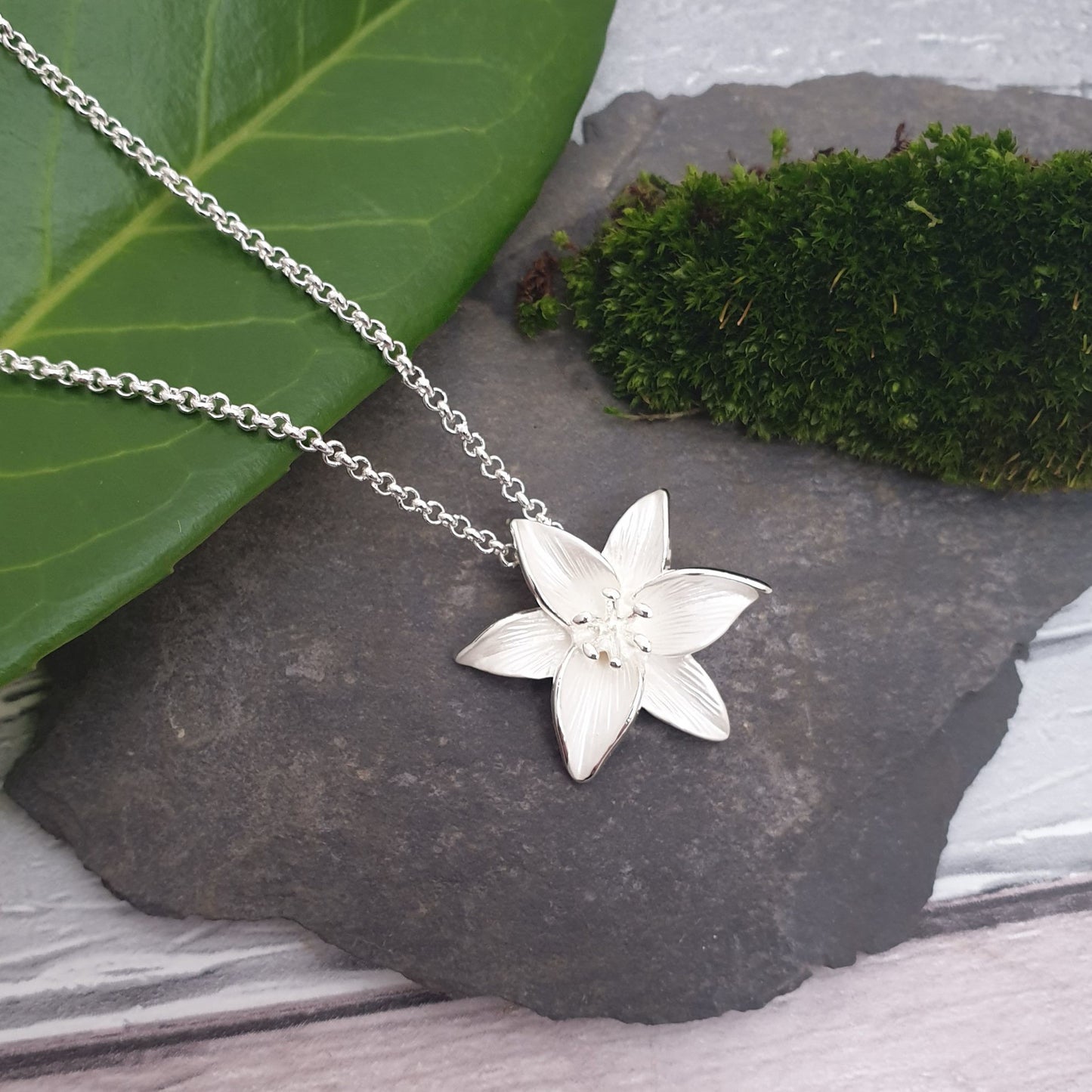 Photo of a single white Madonna Lily as a necklace pendant on a silver chain