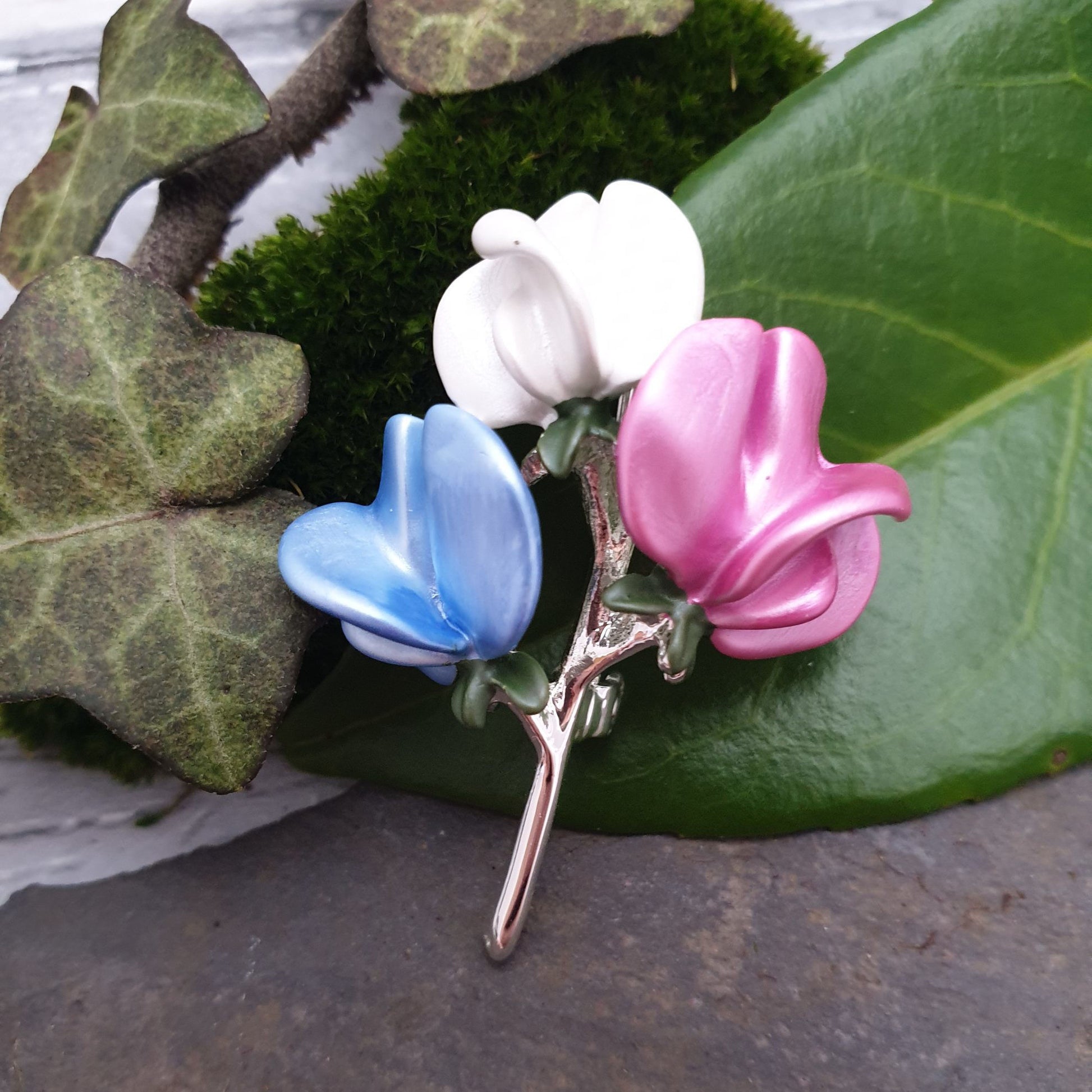 Photo of a minature bouquet of sweet pea flowers on a silver stem as a ladies brooch