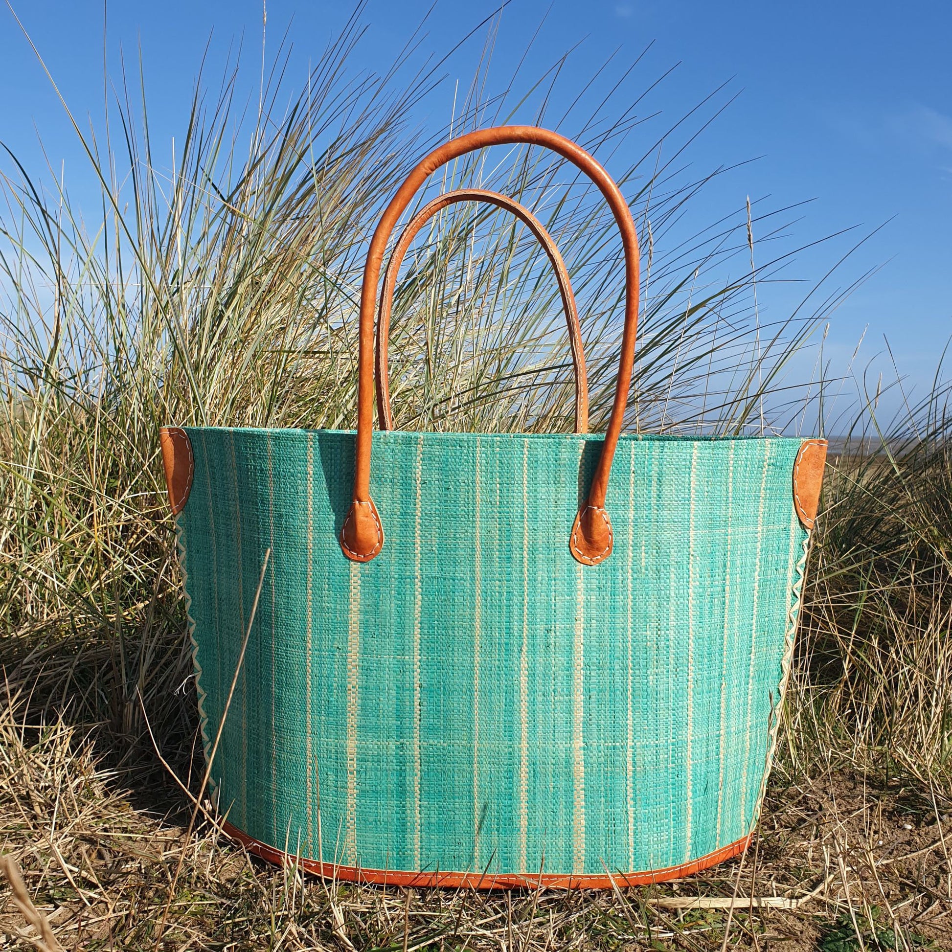Photo of a mint coloured Bato style raffia basket with leather trim and leather handles