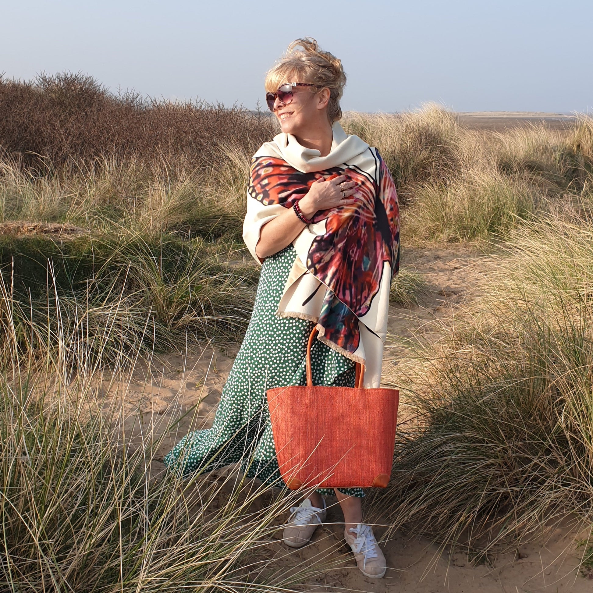 Lady on the beach carrying a red raffia basket 