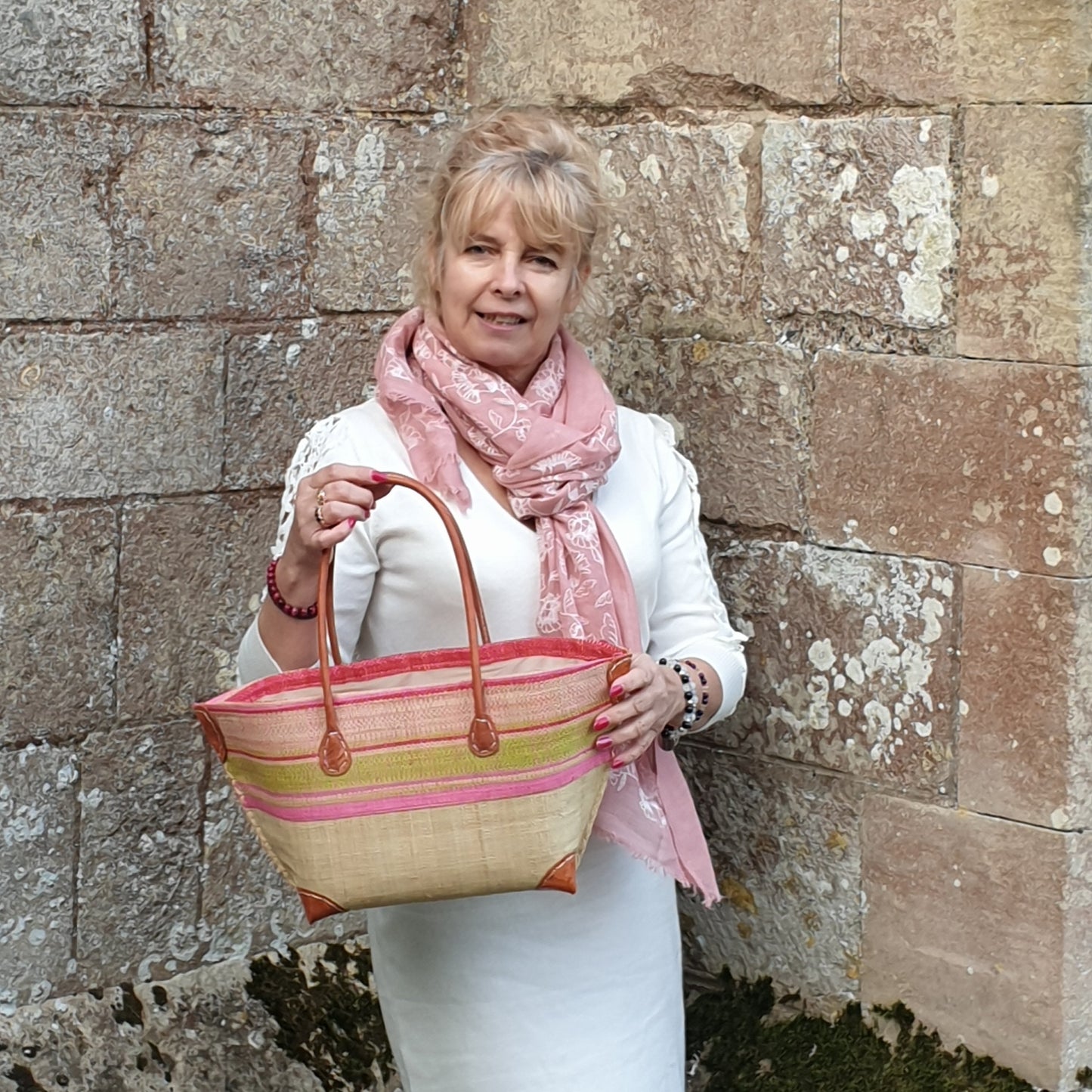 lady carrying a pink and lime striped raffia basket with zip topped and leather handles