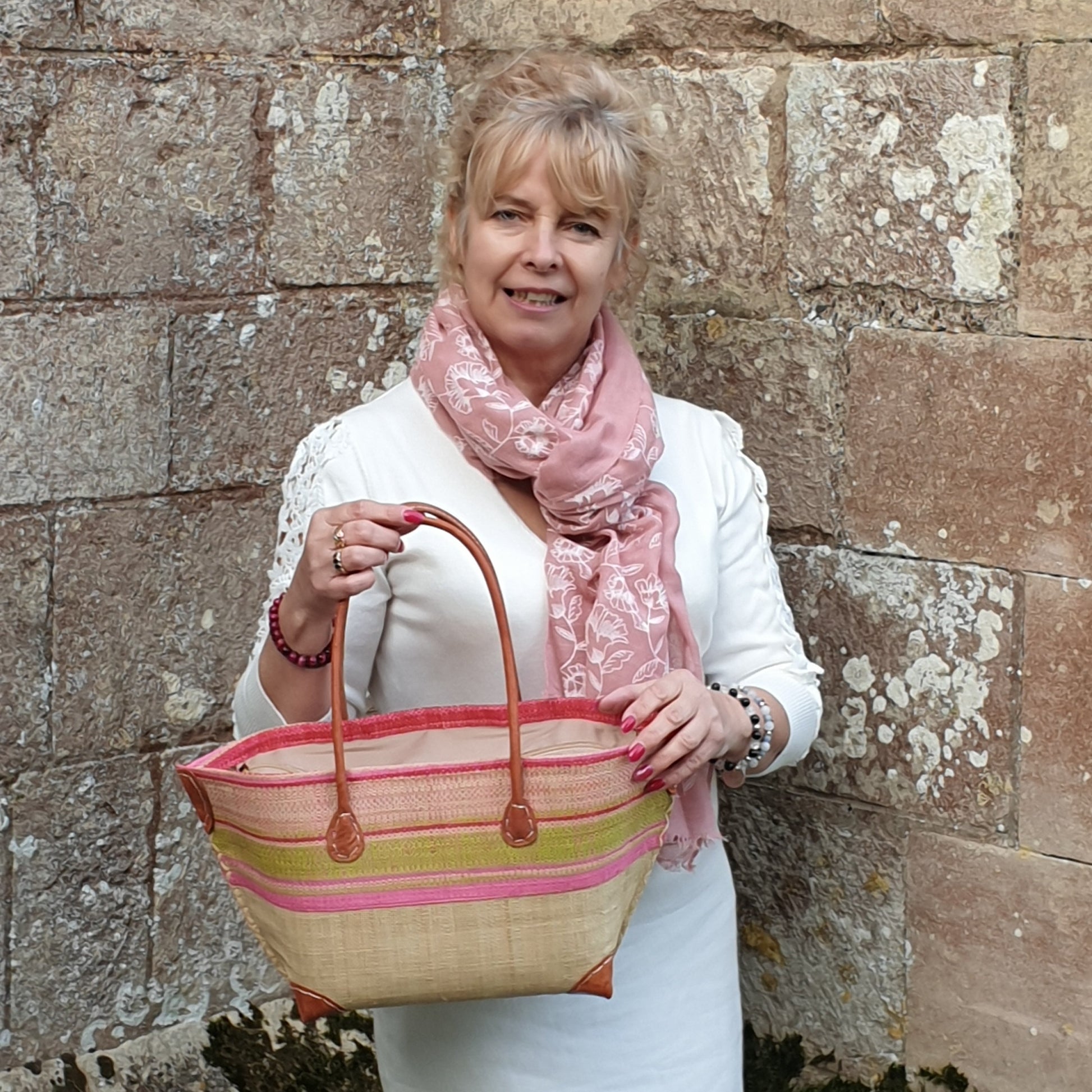 Lady wearing pink scarf and carrying a pink striped raffia basket