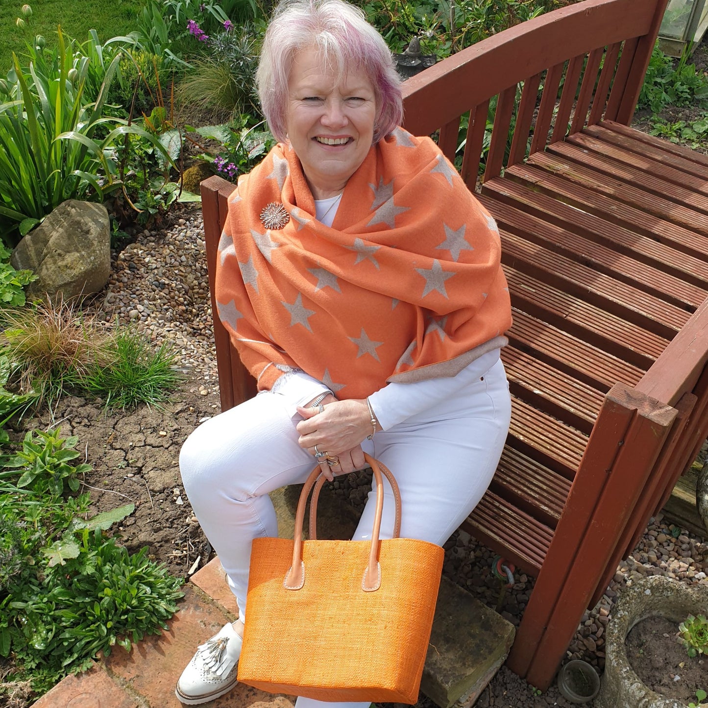 Lady in Orange star print pashmina holding an orange raffia basket with leather handles