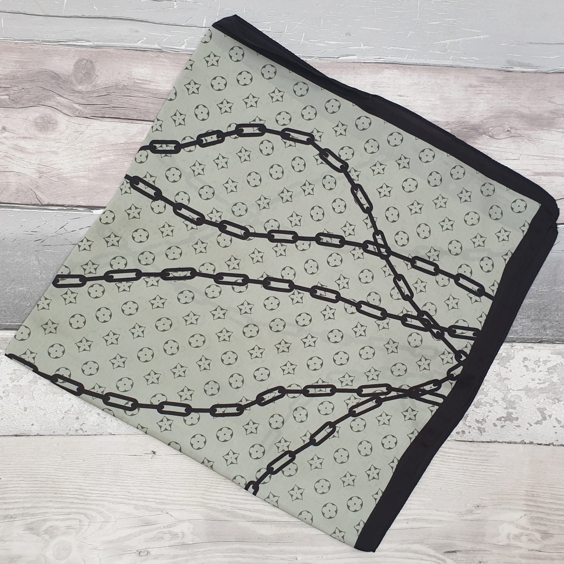 Pale green scarf with solid black trim, decorated with swirls of black chains.